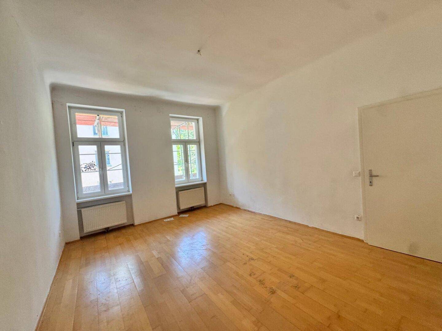 Heller Raum mit Parkettboden und zwei Fenstern, bietet viel Tageslicht.