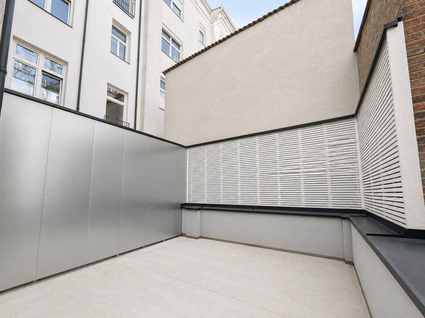 Leere Terrasse mit modernen Wandverkleidungen und Sichtschutz, bereit für individuelle Gestaltung.