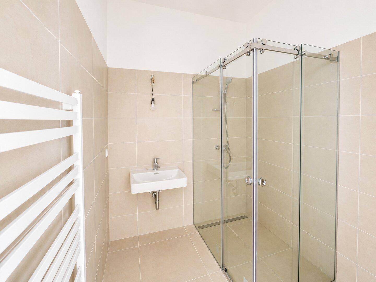 Modernes Badezimmer mit begehbarer Dusche, Einzelwaschbecken und beheiztem Handtuchhalter.
