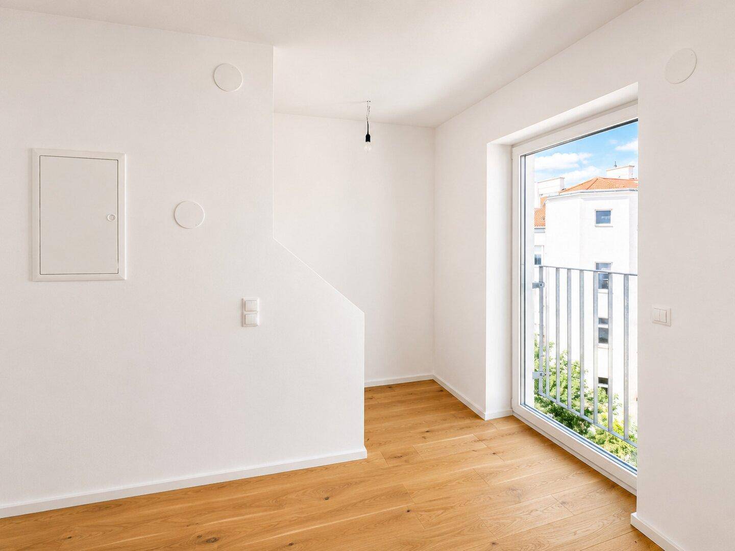 Heller Raum mit Holzboden und Zugang zu einem französischen Balkon, der viel Licht bietet.