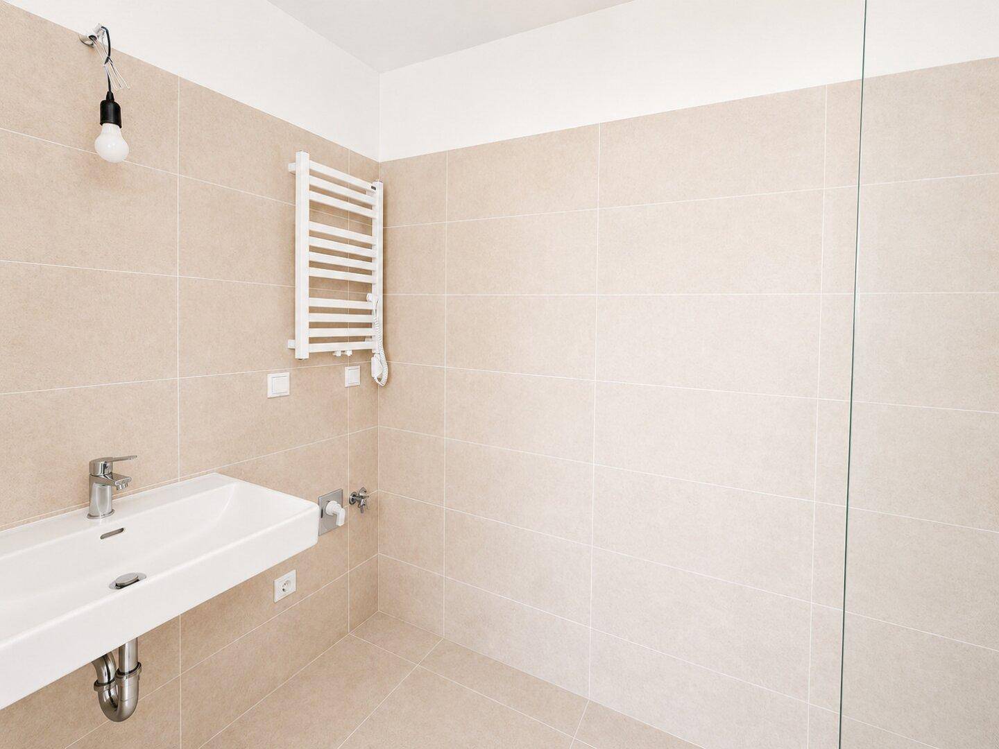 Modernes Badezimmer mit beigefarbenen Fliesen, einem einzelnen Waschbecken und beheiztem Handtuchhalter.