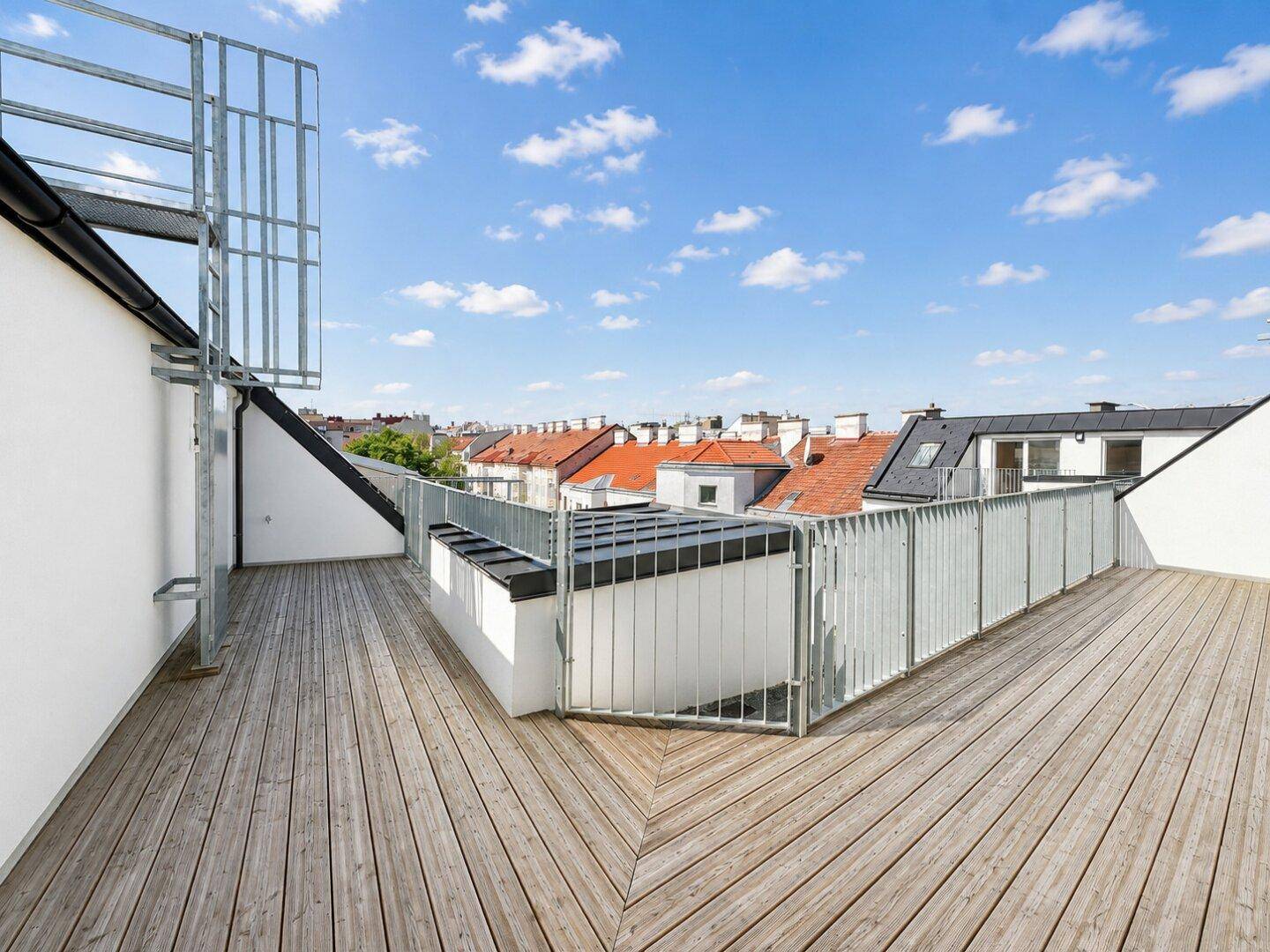 Große Dachterrasse mit Holzbelag und Panoramablick über die umliegenden Dächer der Stadt.