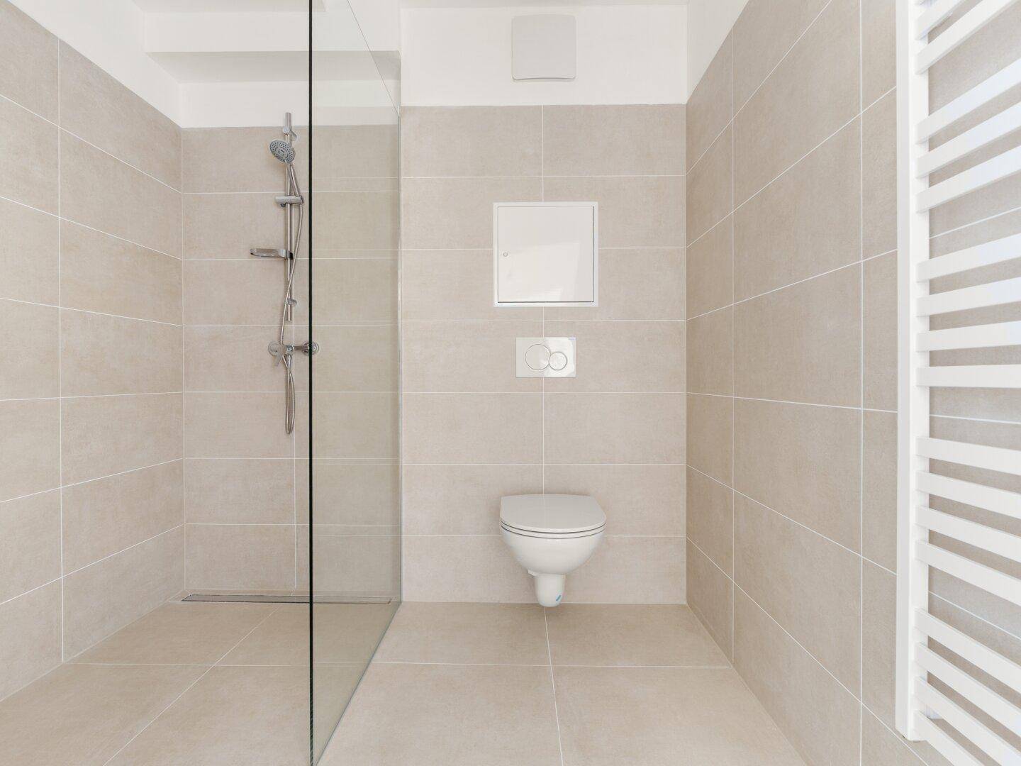 Modernes Badezimmer mit beigefarbenen Fliesen, ebenerdiger Dusche und Wand-WC.