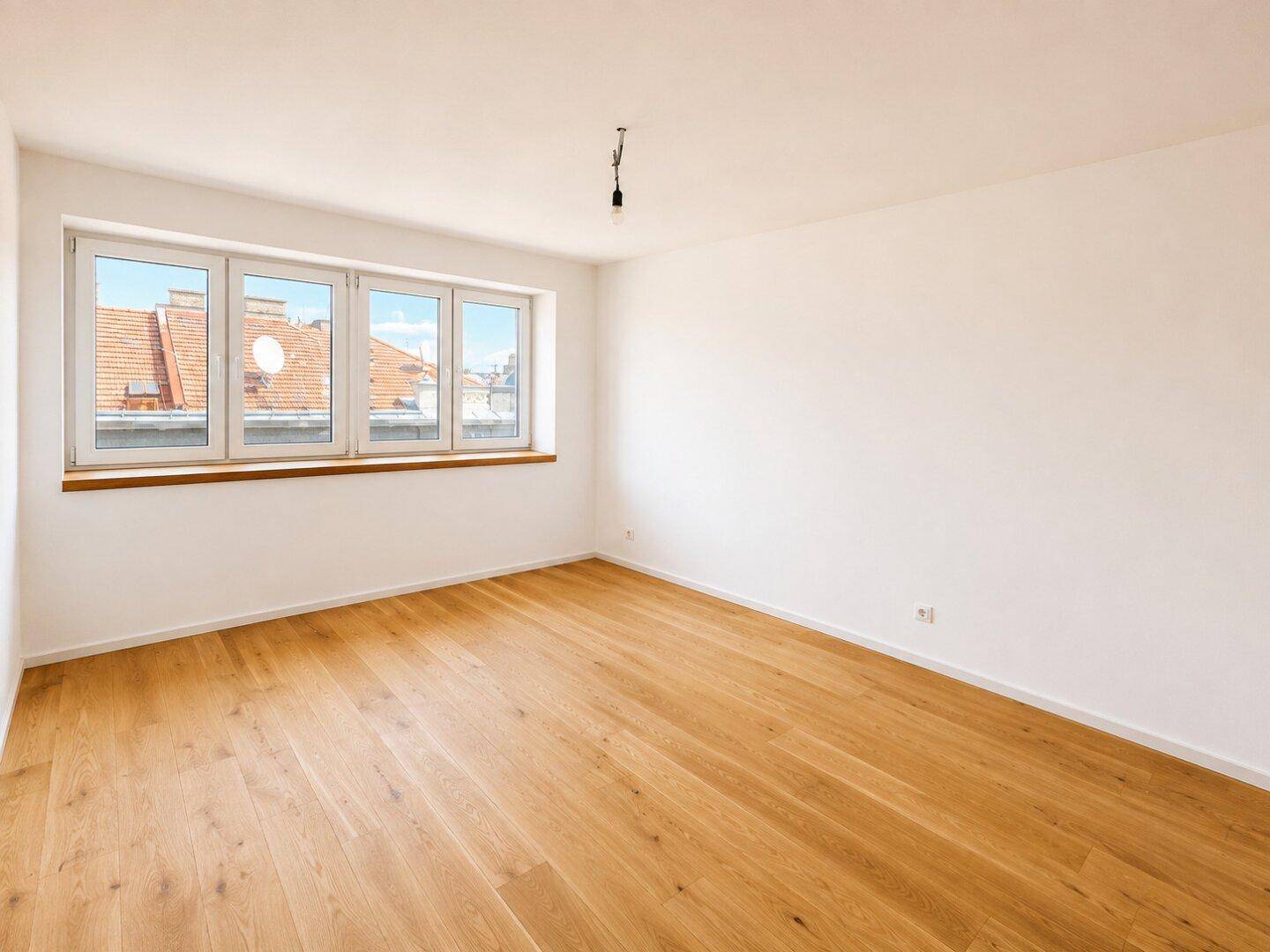 Geräumiges Zimmer mit Holzboden und weitem Blick über die Dächer der Stadt.