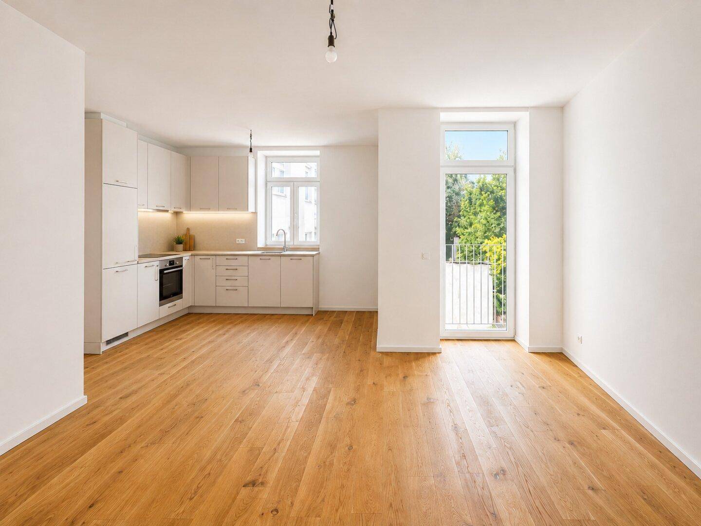 Moderne Einbauküche in hellem Wohnbereich mit Parkettboden und Zugang zum französischen Balkon.