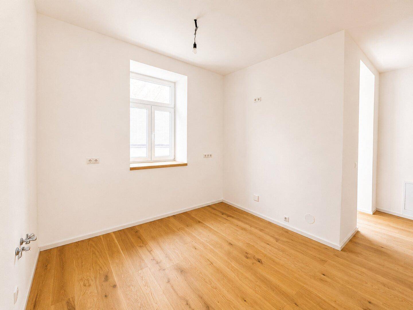 Heller Raum mit Parkettboden und Fenster, vorbereitet für Installationen, bietet flexible Nutzungsmöglichkeiten.
