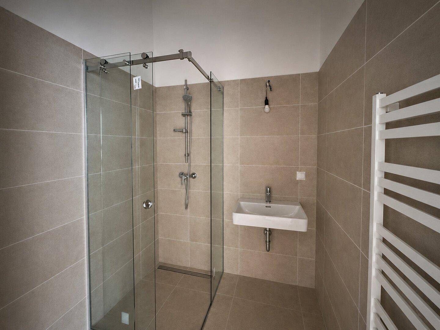 Modernes Badezimmer mit begehbarer Dusche, beigefarbenen Fliesen und Handtuchheizkörper.