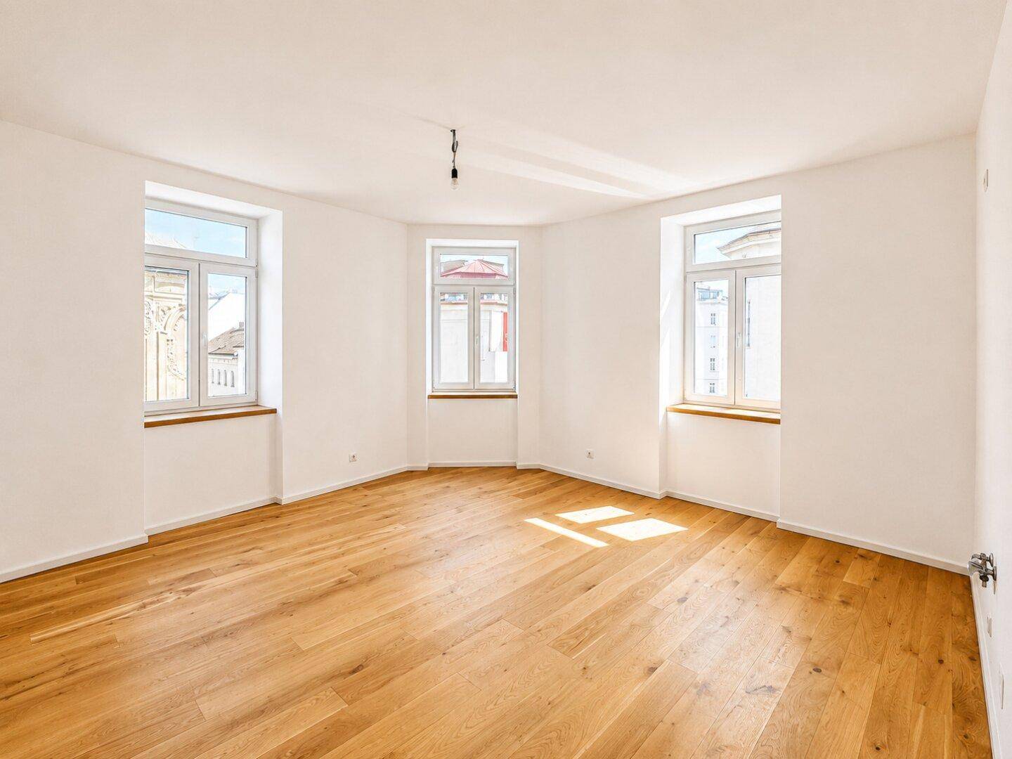 Großes, helles Zimmer mit Parkettboden und vielen Fenstern, bietet vielseitige Nutzungsmöglichkeiten.
