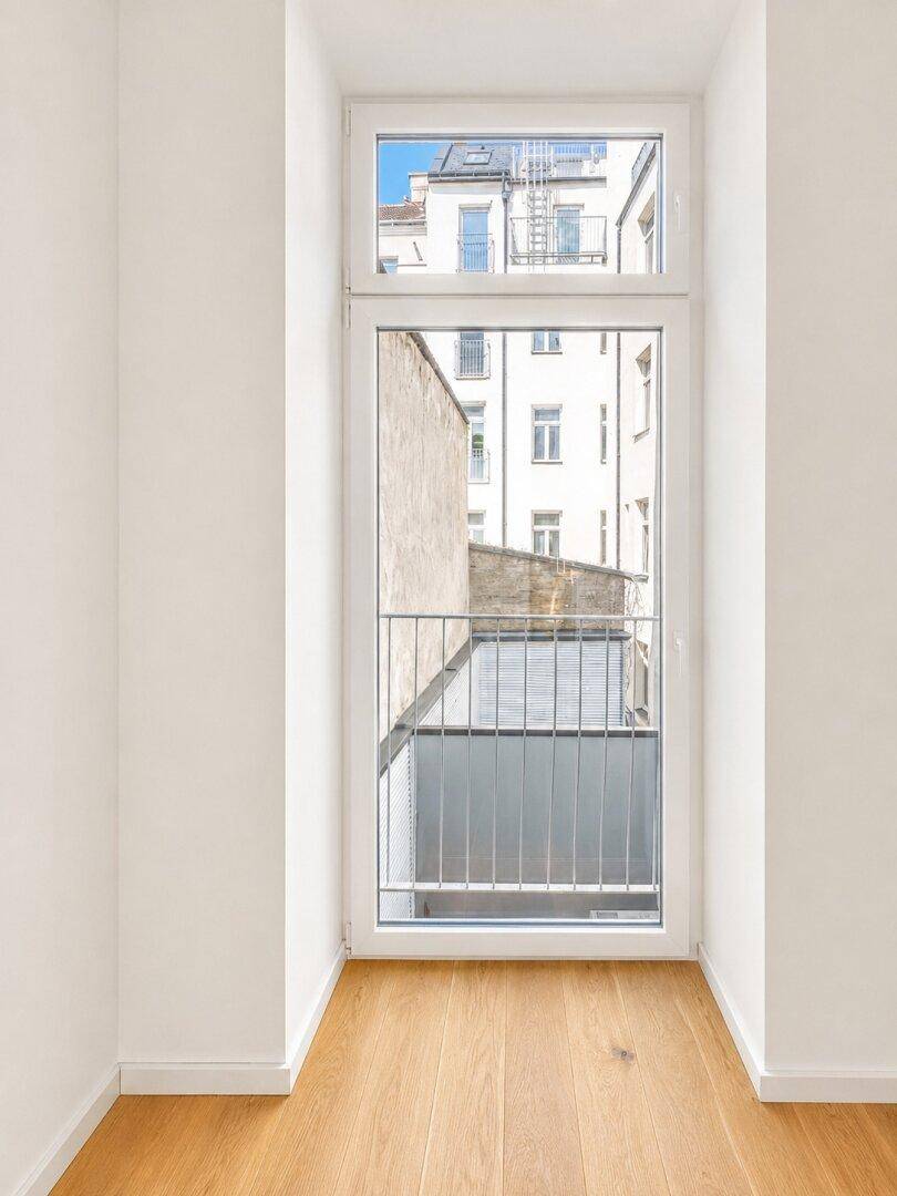 Französischer Balkon mit Blick auf den Innenhof und umliegende Gebäude.
