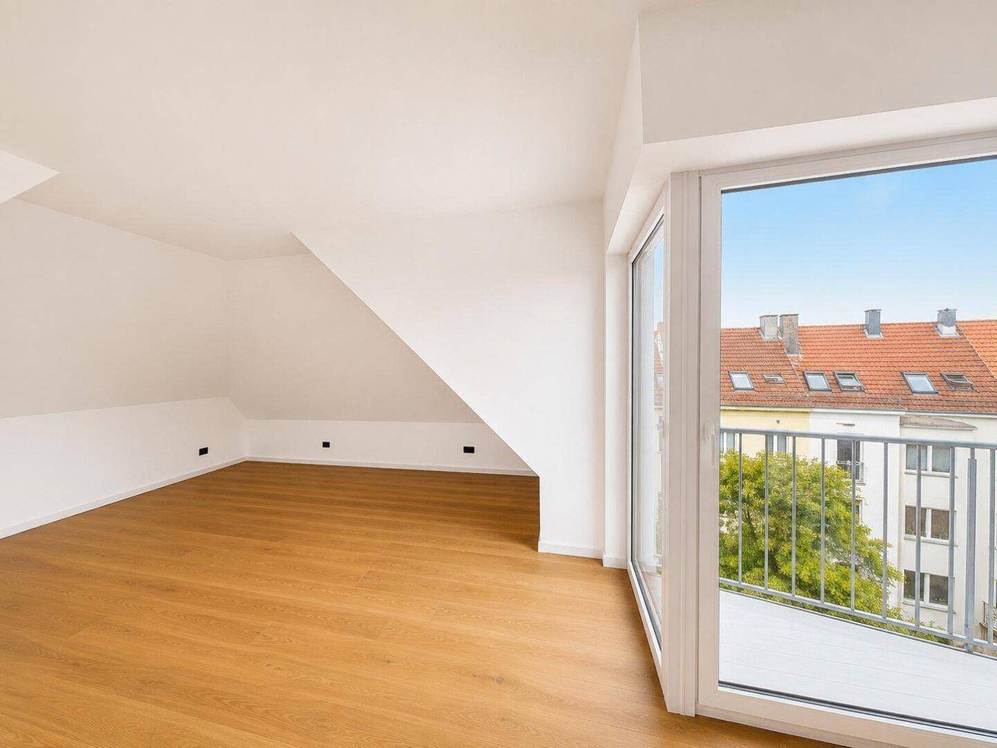 Heller, unmöblierter Raum mit Holzboden und Balkonzugang, ideal für Schlaf- oder Wohnbereich.