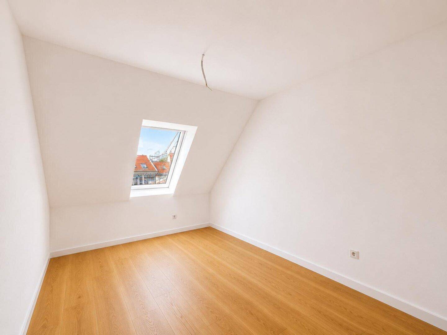 Kleinerer, heller Raum mit Holzboden und einem Dachfenster, ideal als Kinder- oder Arbeitszimmer.