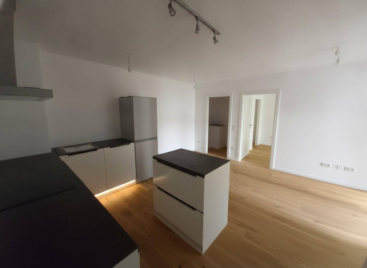 Leere Küche mit teilweiser Installation, Kühlschrank und Holzboden, bereit für die Fertigstellung.