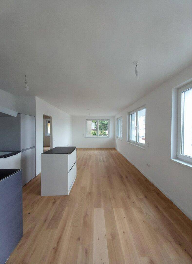 Langer, offener Wohnbereich mit Holzboden und vielen Fenstern für natürliche Belichtung.