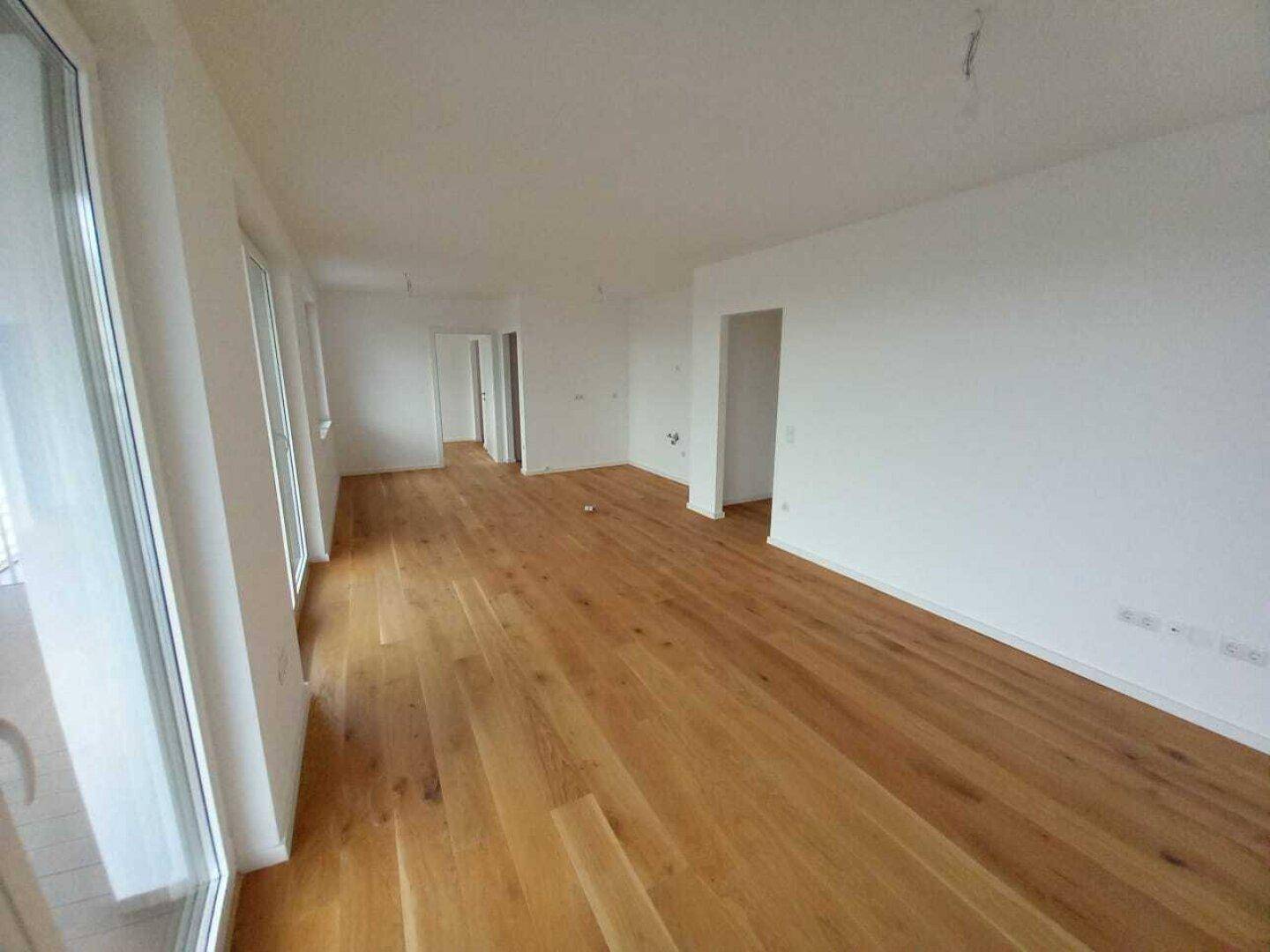 Großer, heller Wohnbereich mit Holzdielenboden und Zugang zu einem Außenbereich.