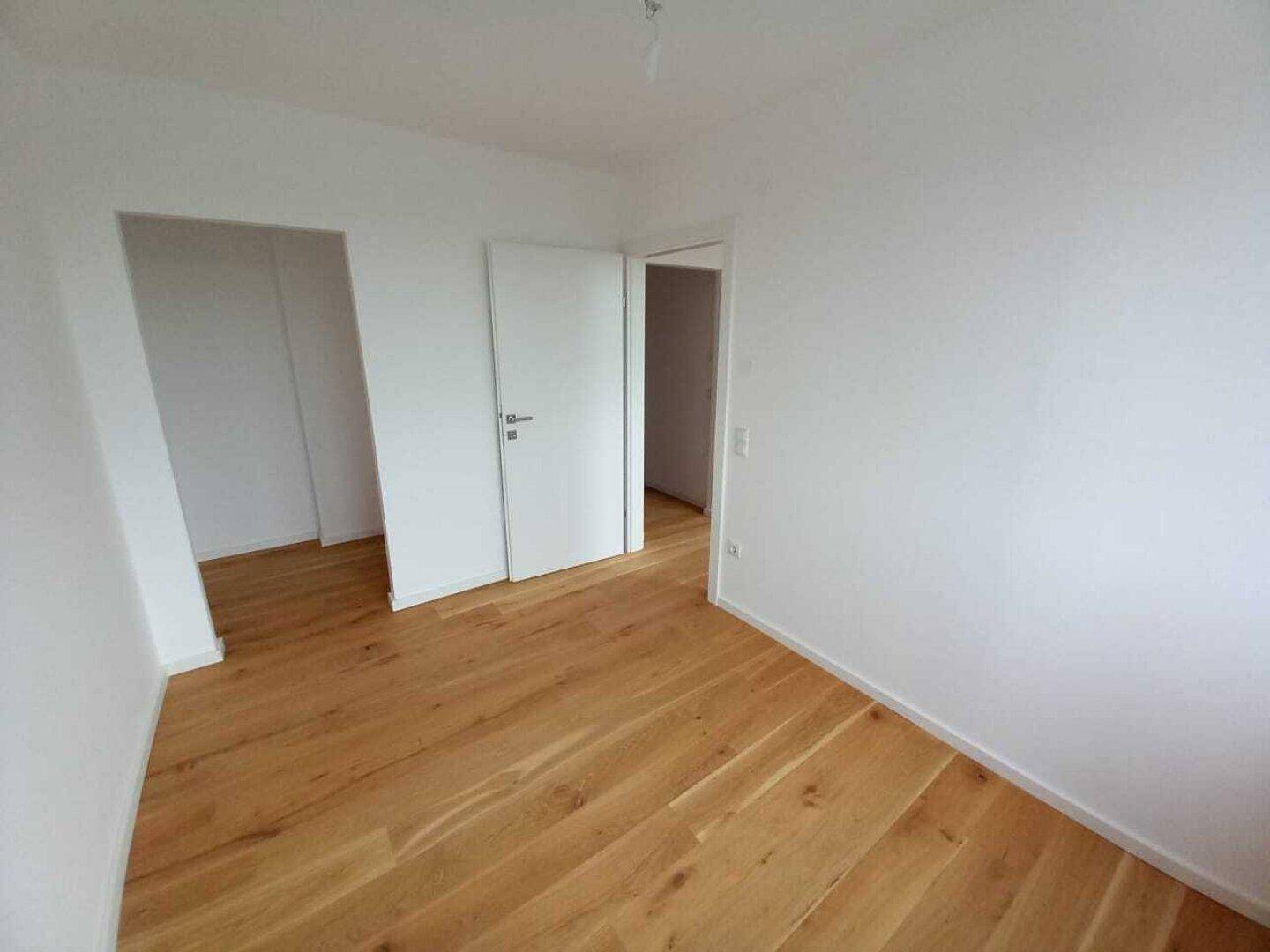 Leerer Raum mit Holzdielenboden und zwei Türen, bereit zur individuellen Gestaltung.