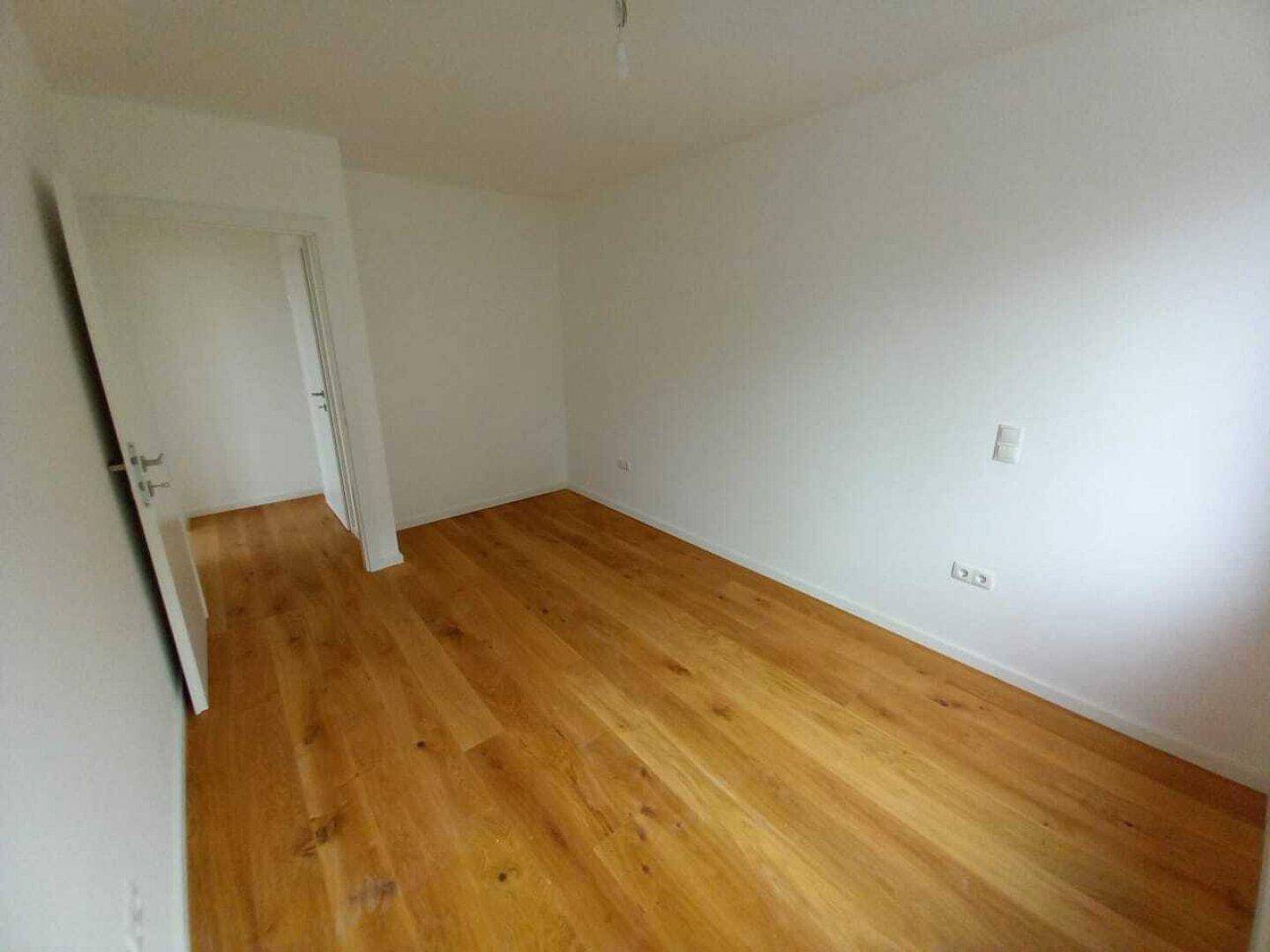 Unmöblierter Raum mit Holzdielenboden und weiß gestrichenen Wänden, ideal für verschiedene Nutzungen.