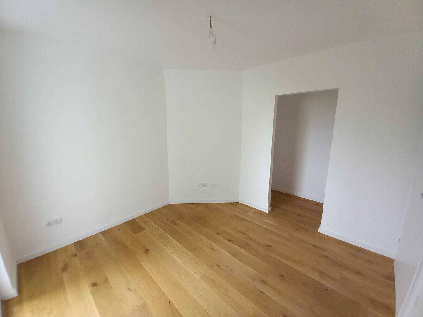 Leeres Zimmer mit hellem Holzboden und weißen Wänden, bietet vielseitige Nutzungsmöglichkeiten.
