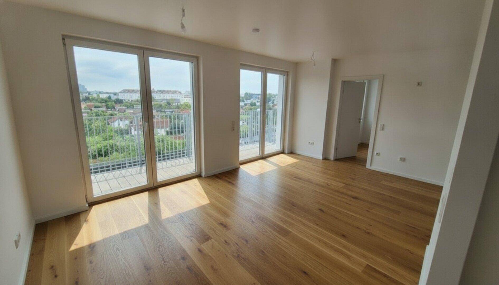 Geräumiges, helles Wohnzimmer mit großen Fenstern und Zugang zu einem Balkon, bietet viel Tageslicht.