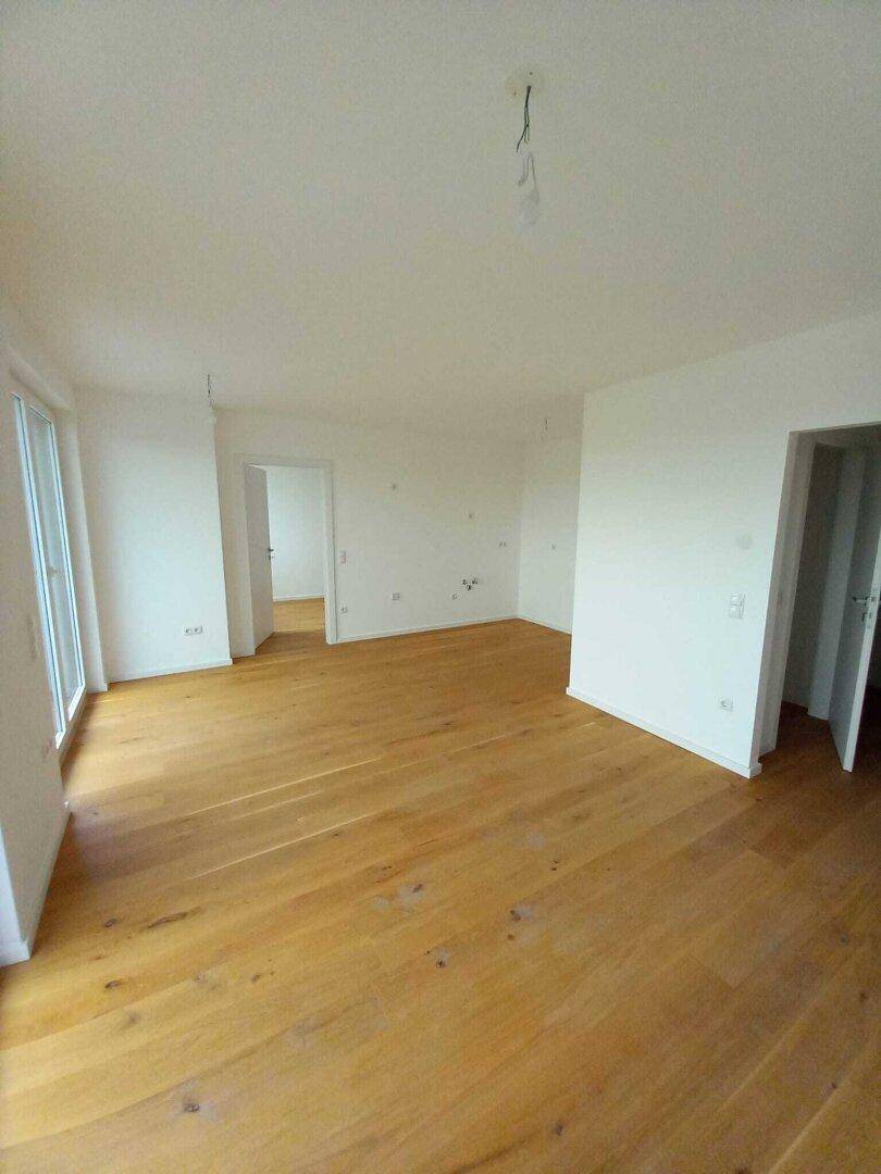 Geräumiger, heller Raum mit Holzboden und mehreren Türöffnungen, bereit zur individuellen Gestaltung.