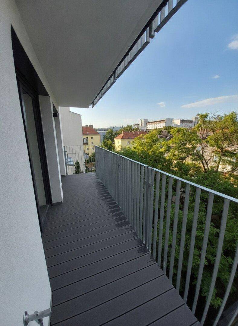 Geräumiger Balkon mit modernem Geländer und weitem Blick über die Stadt und grüne Umgebung.