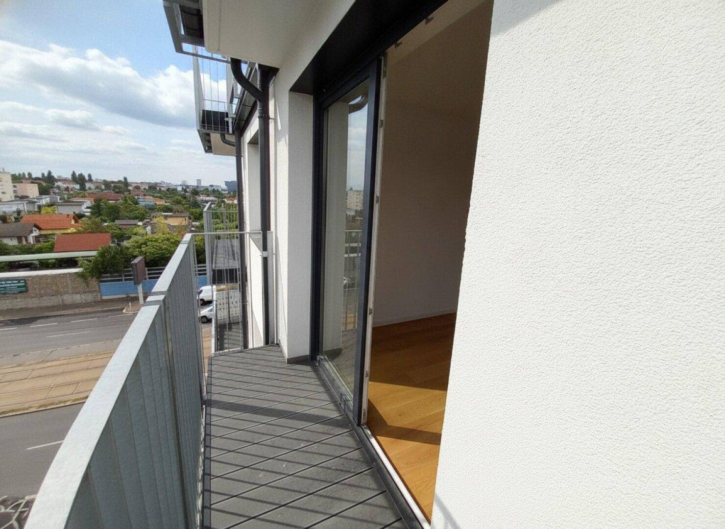 Moderner Balkon mit Metallgeländer und weitem Blick über die städtische Umgebung.
