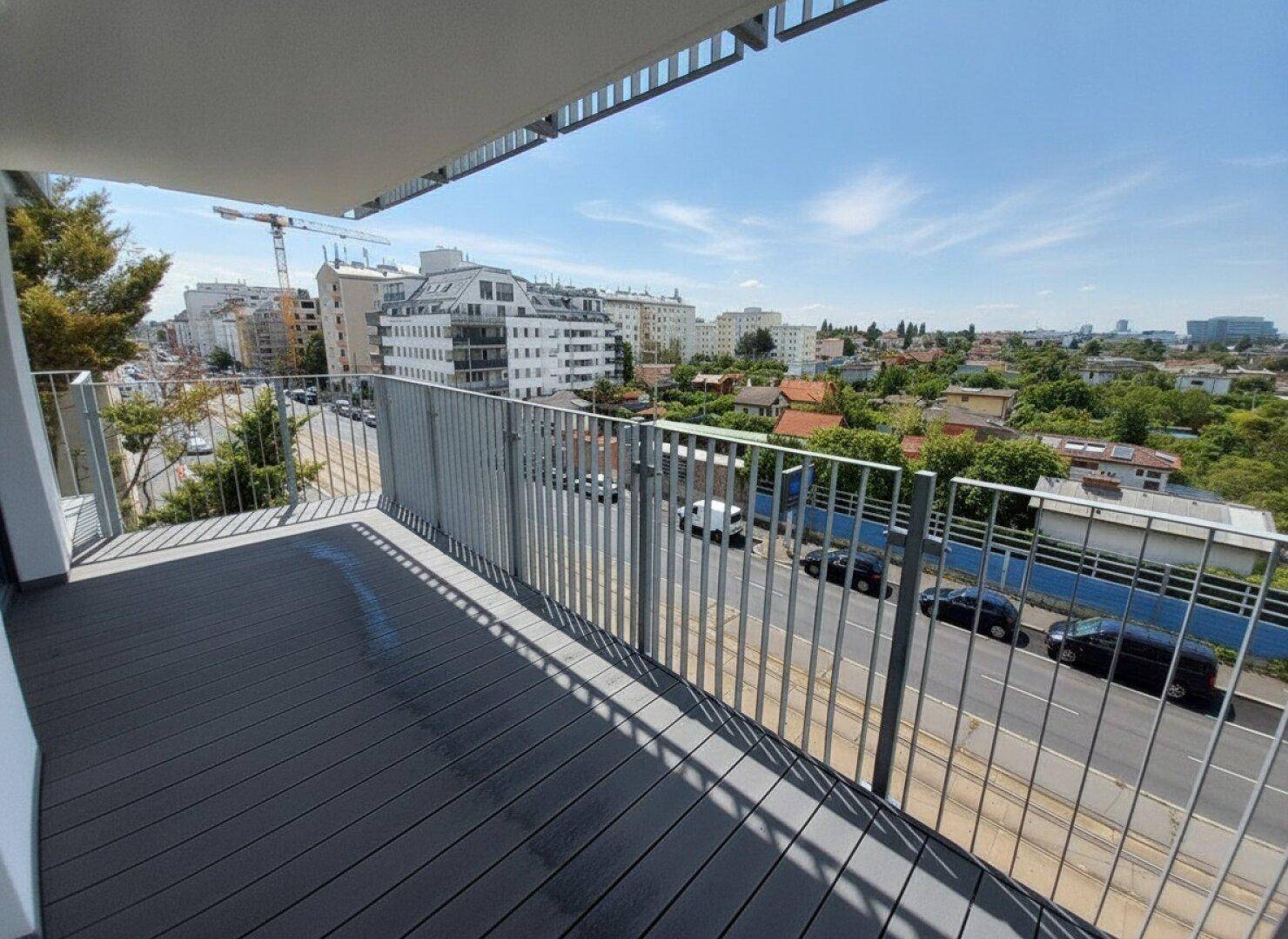Geräumiger Balkon mit modernem Bodenbelag und weitem Blick über die Stadt und die Umgebung.