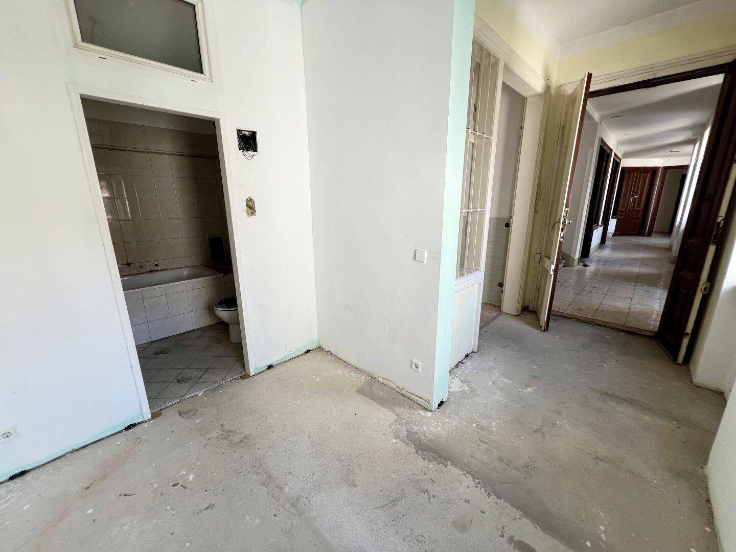 Offener Bereich oder Flur mit Betonboden, der Zugang zu mehreren Zimmern und einem Badezimmer bietet.