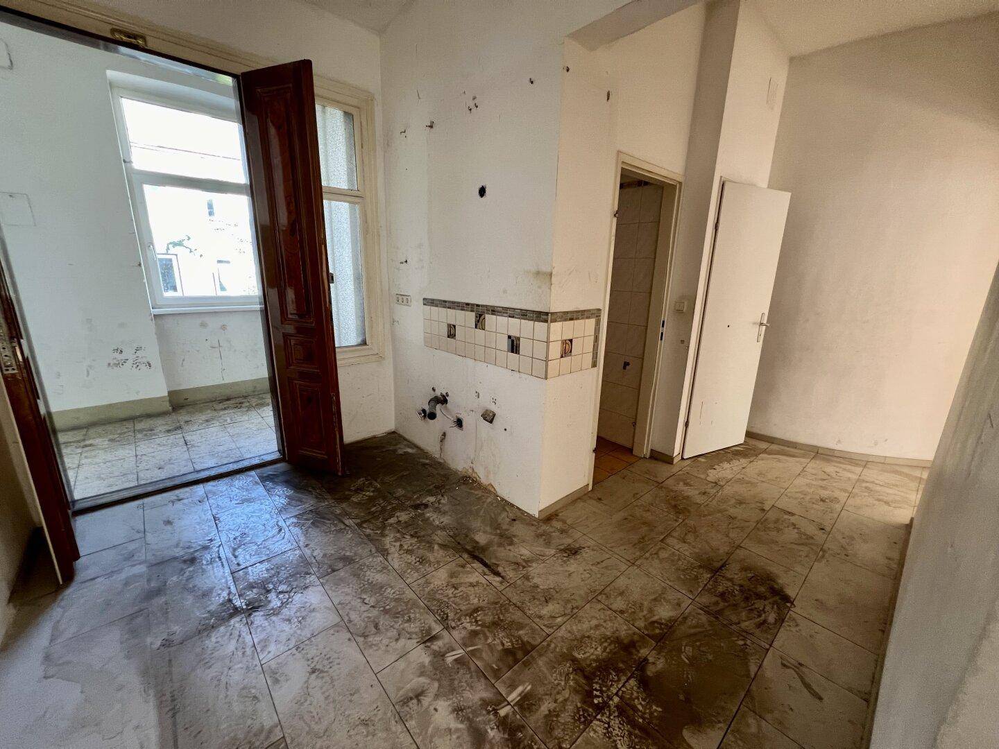Unfertige Küche mit Zugang zu einem Außenbereich und Fliesen an der Wand.