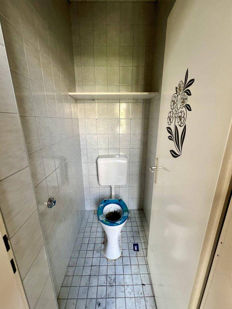 Kleines WC mit Fliesen an Wänden und Boden sowie einer einfachen Toilette.