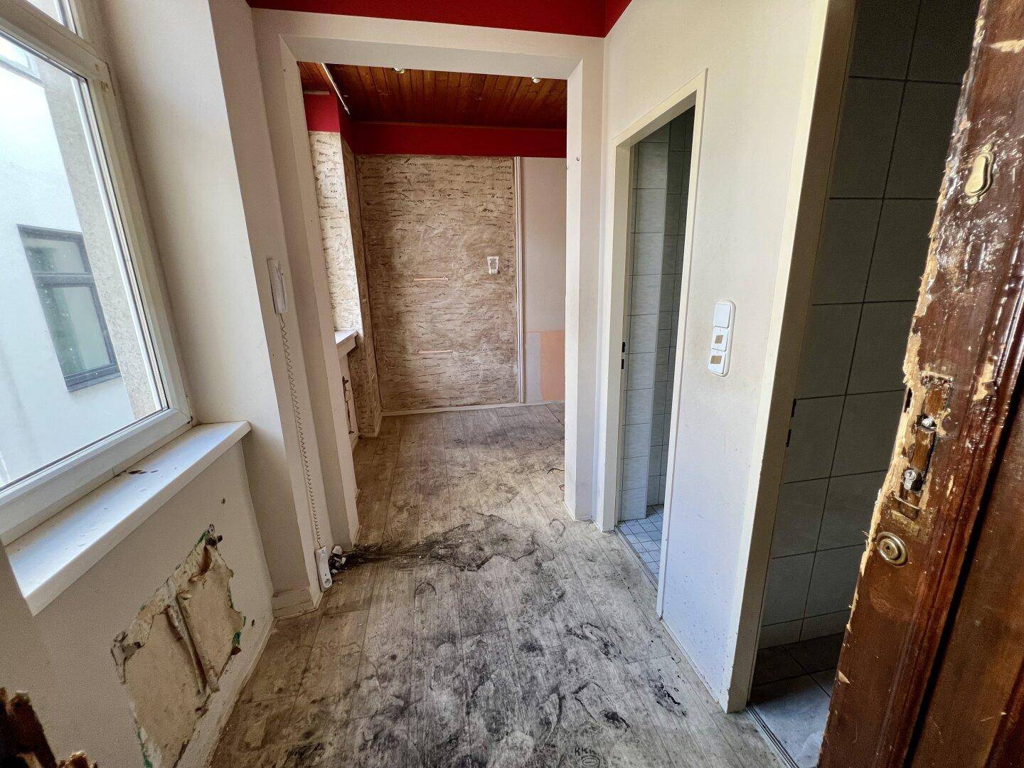 Flur mit Fenster und Zugang zu weiteren Räumen, teilweise in Renovierung.