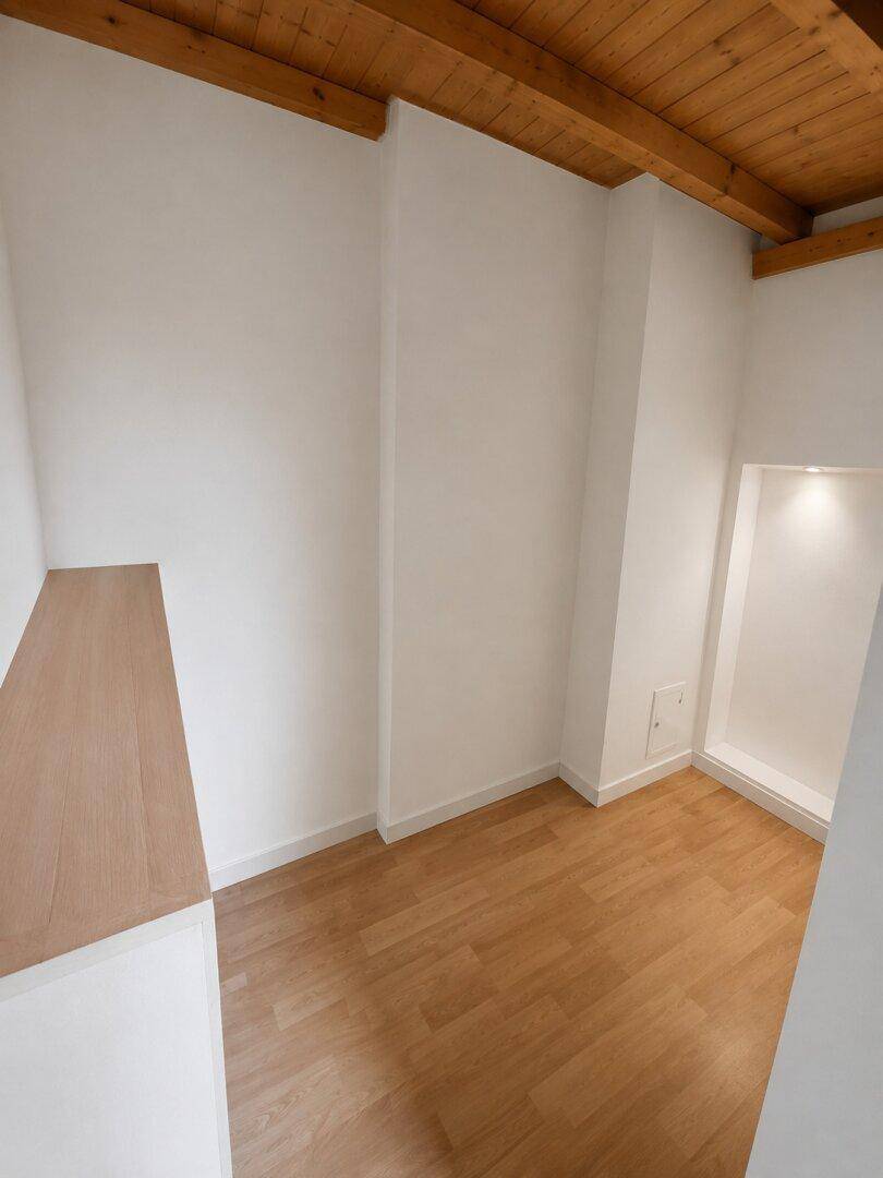 Gemütliches Zimmer mit Holzbalkendecke und hellem Laminatboden.