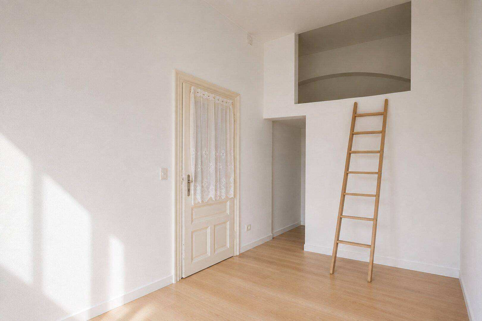 Helles Zimmer mit Holzboden und Leiter zu einem erhöhten Schlafbereich.