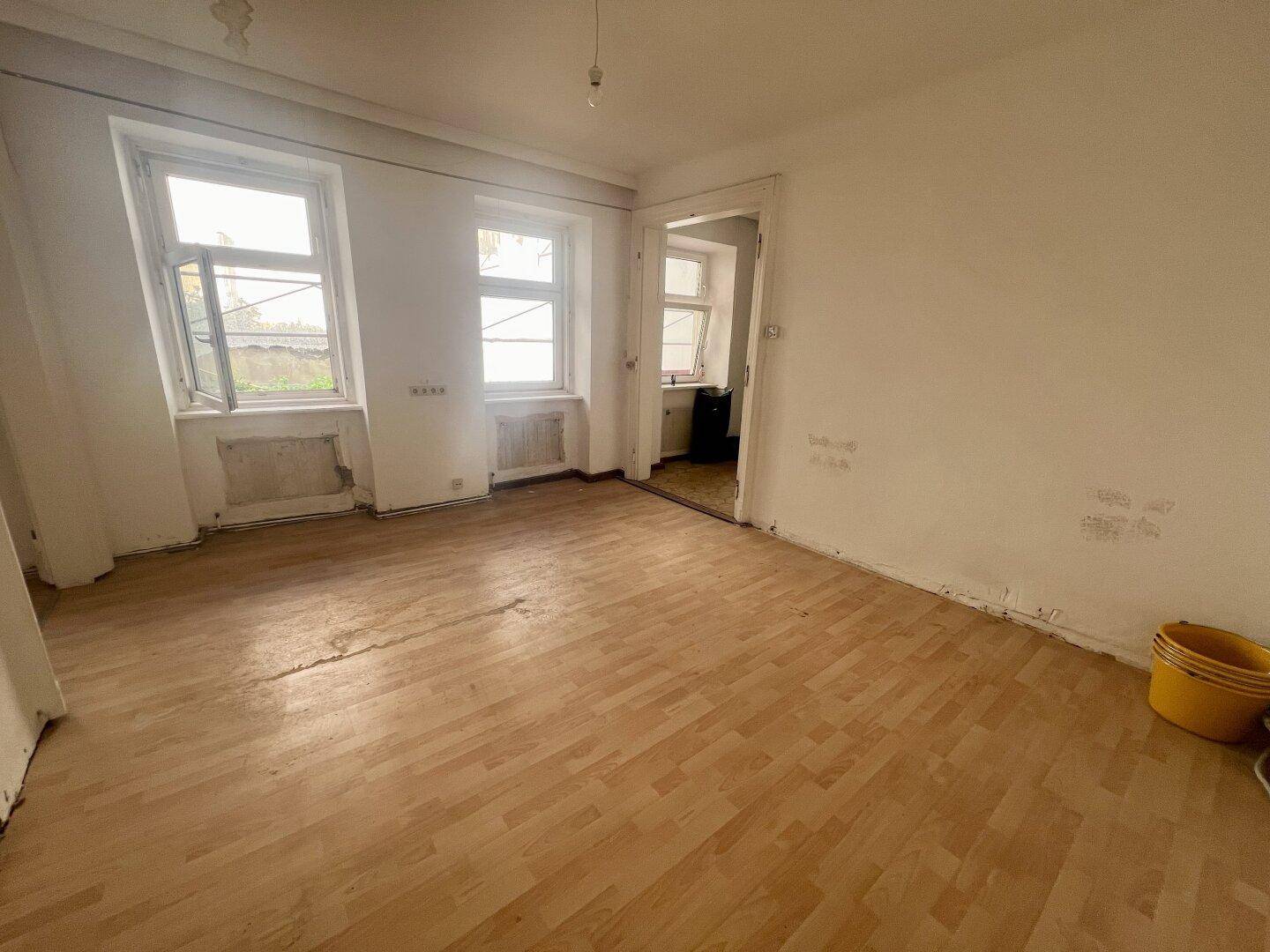 Heller, leerer Raum mit Holzboden und geöffneten Fenstern, ideal für eine Neugestaltung.