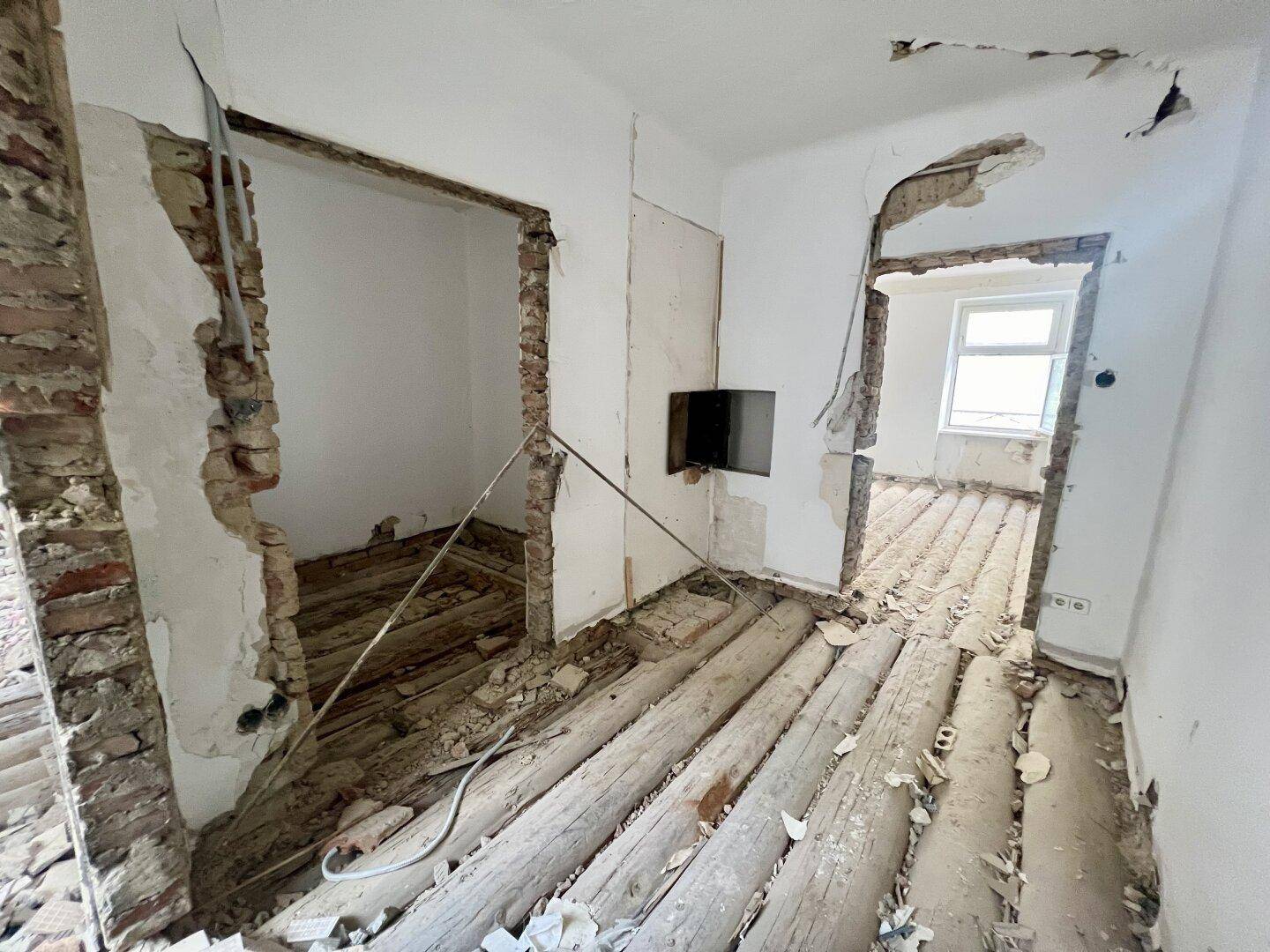 Innenraum in Sanierung mit freigelegten Ziegelwänden und Holzbalken, bereit für den Umbau.