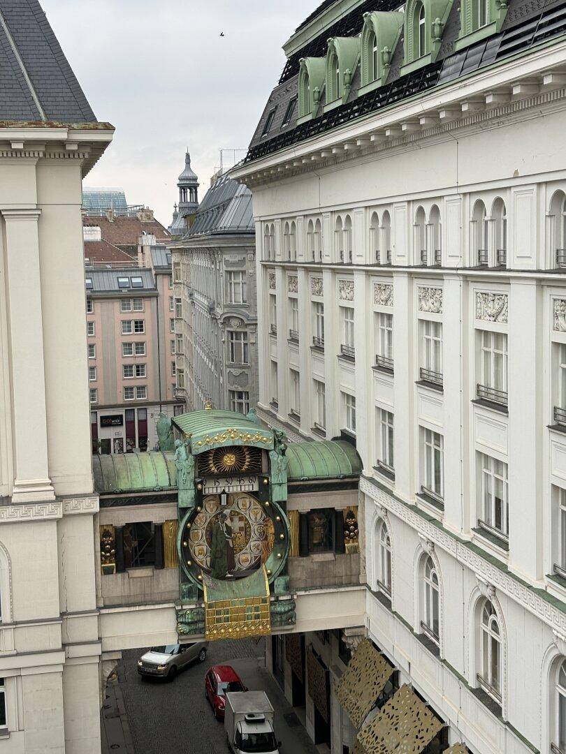 Historische Gebäude mit dem Ankeruhr-Kunstwerk und belebter Straße in der Wiener Innenstadt.