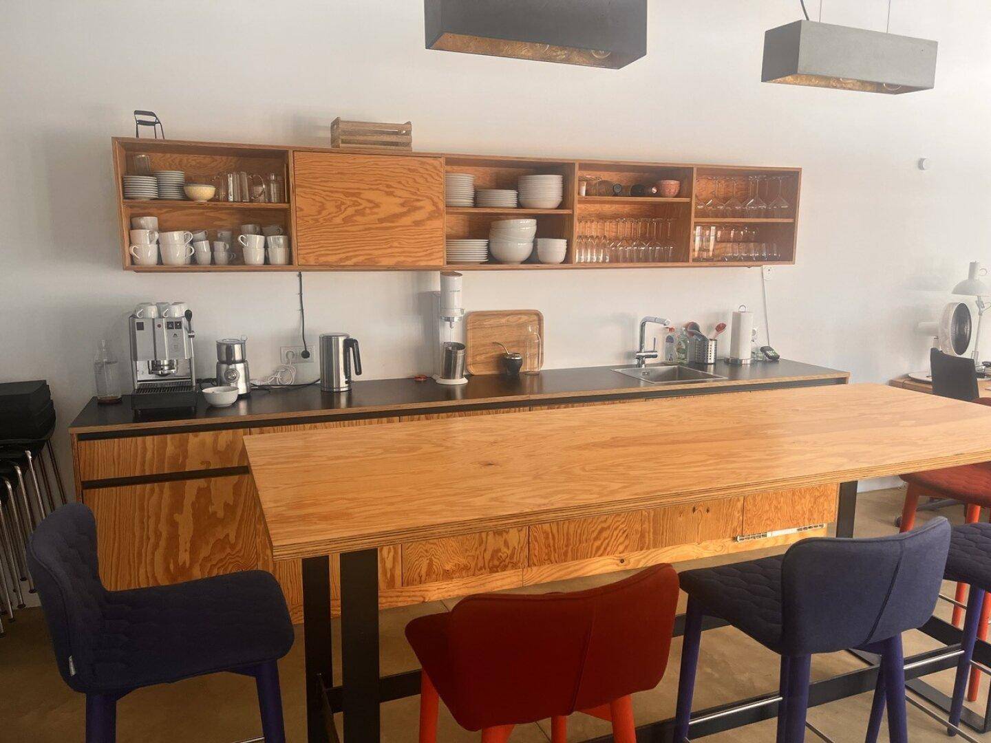 Moderne Küche mit Holzelementen, schwarzer Arbeitsplatte und integrierter Bar mit Sitzgelegenheiten.