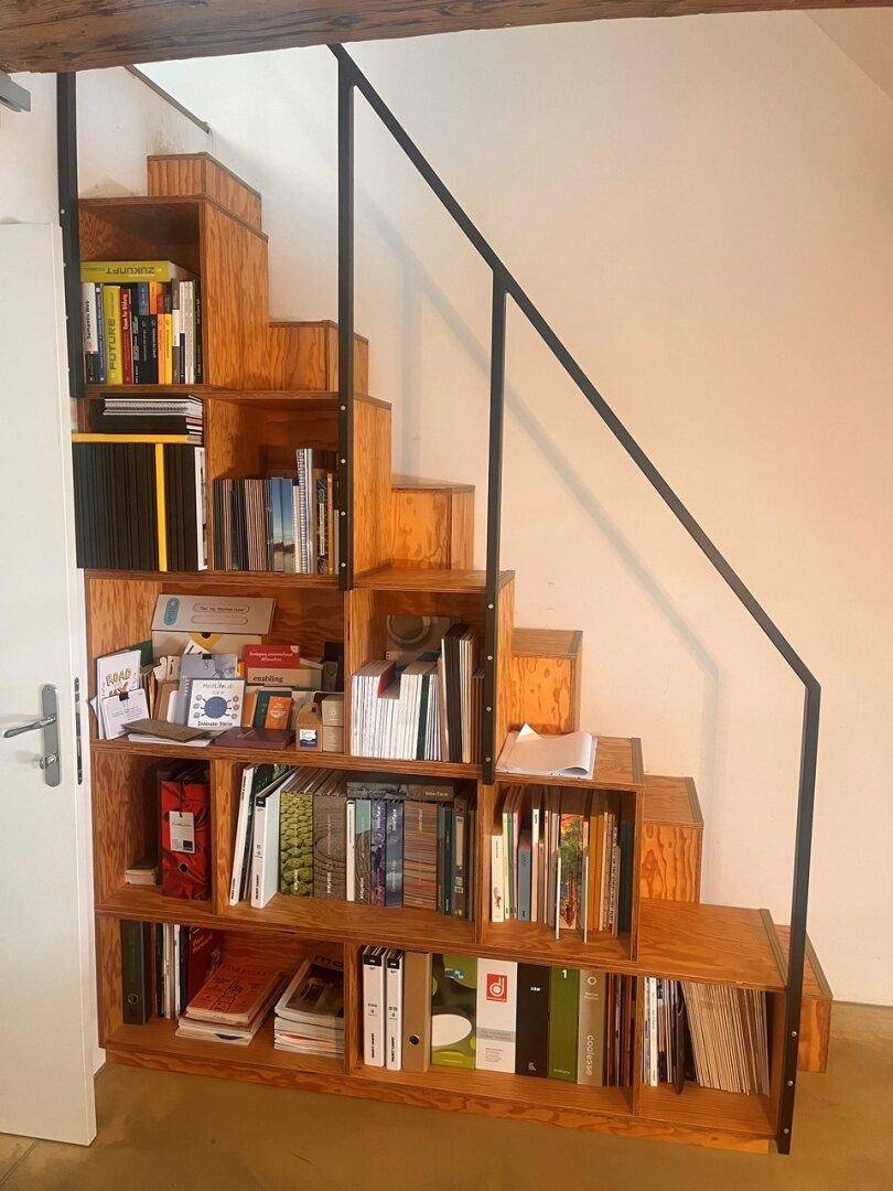 Einzigartige Holztreppe mit integrierten Bücherregalen und schwarzem Metallgeländer.