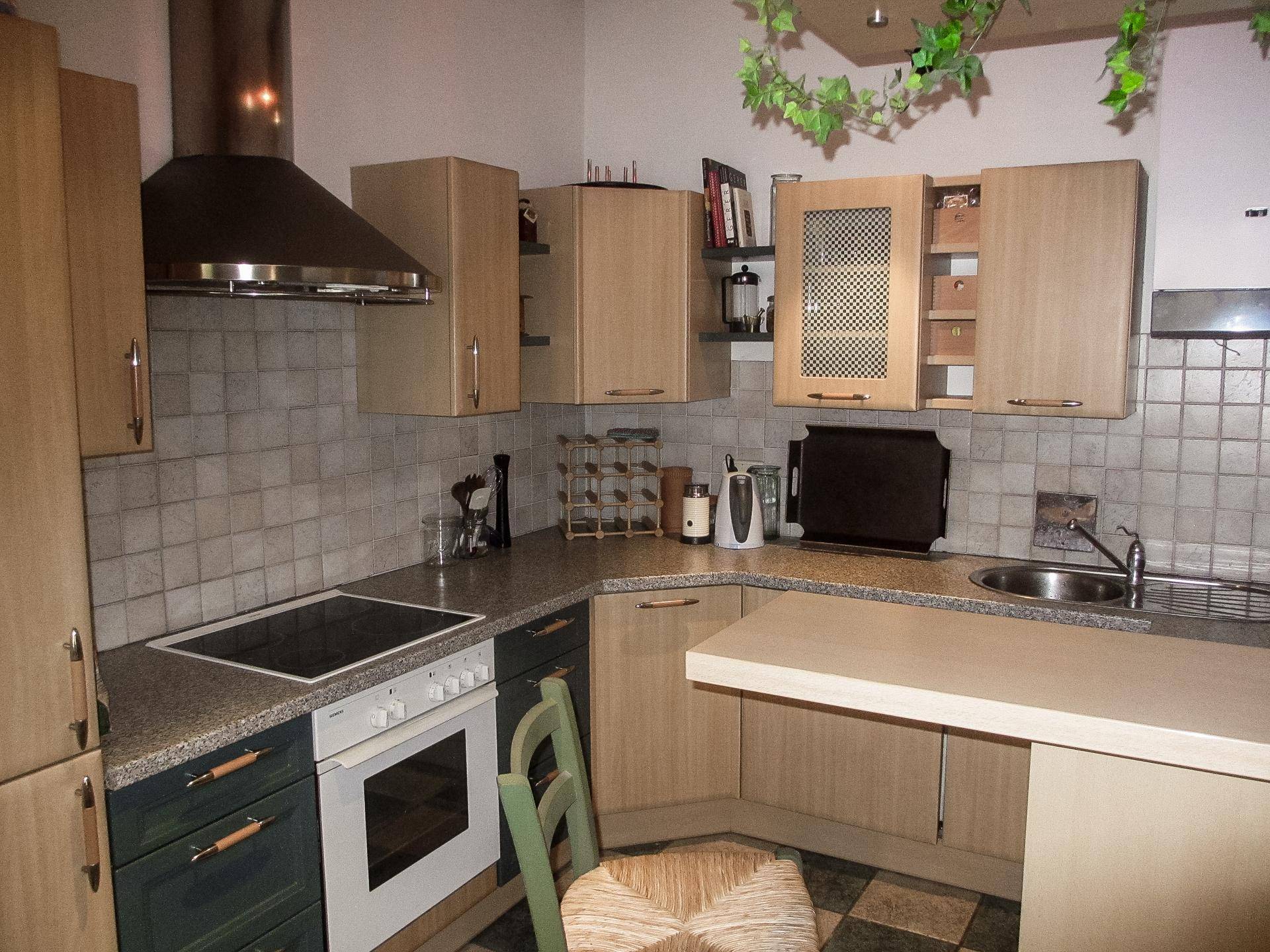 Funktionale Küche mit hellen Holzschränken, Granitarbeitsplatte und integrierten Geräten.