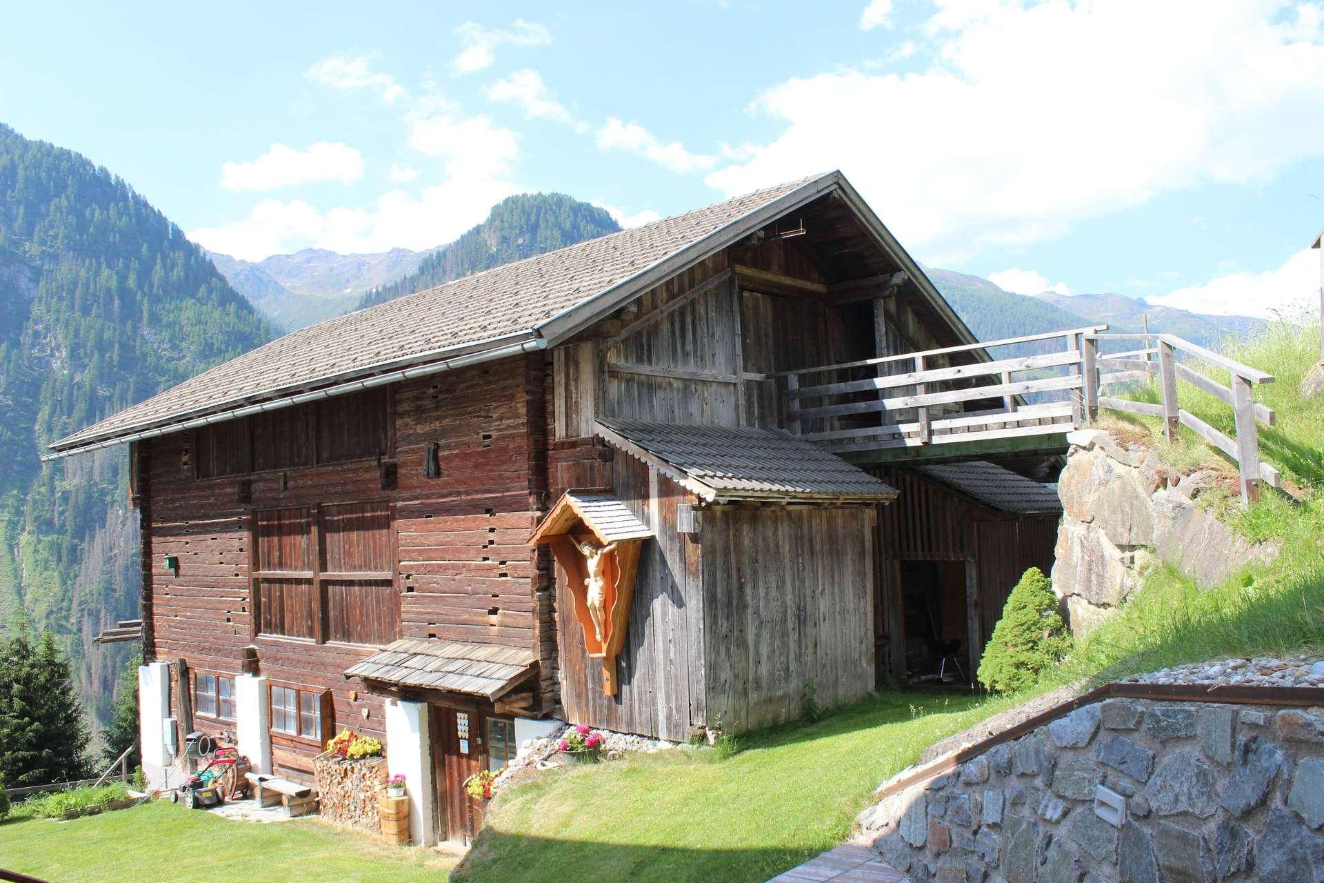 Rustikales Holzgebäude mit traditioneller Dekoration, eingebettet in eine weite grüne Berglandschaft.