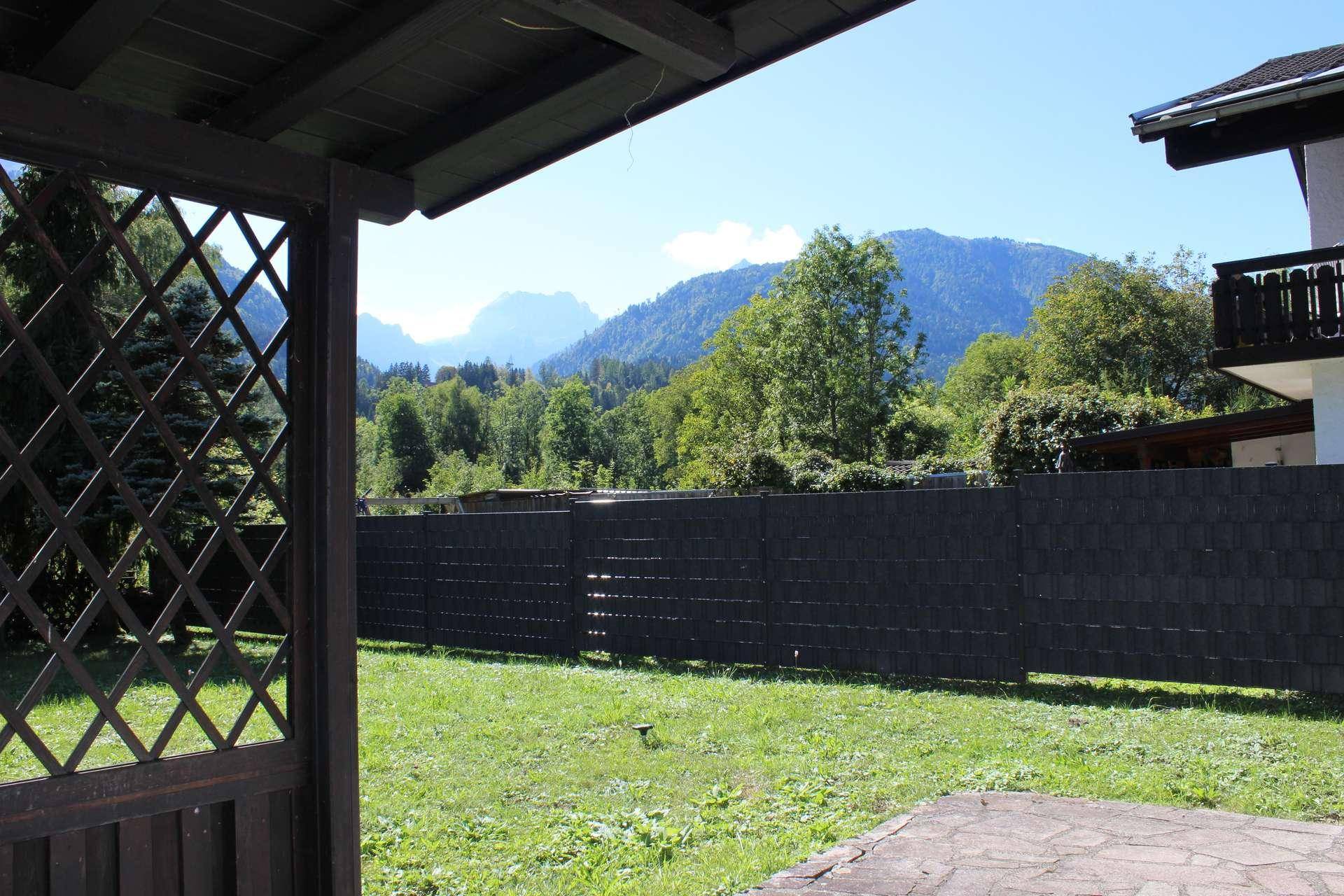 Überdachte Terrasse mit Blick auf die umliegenden Berge und grüne Landschaft.