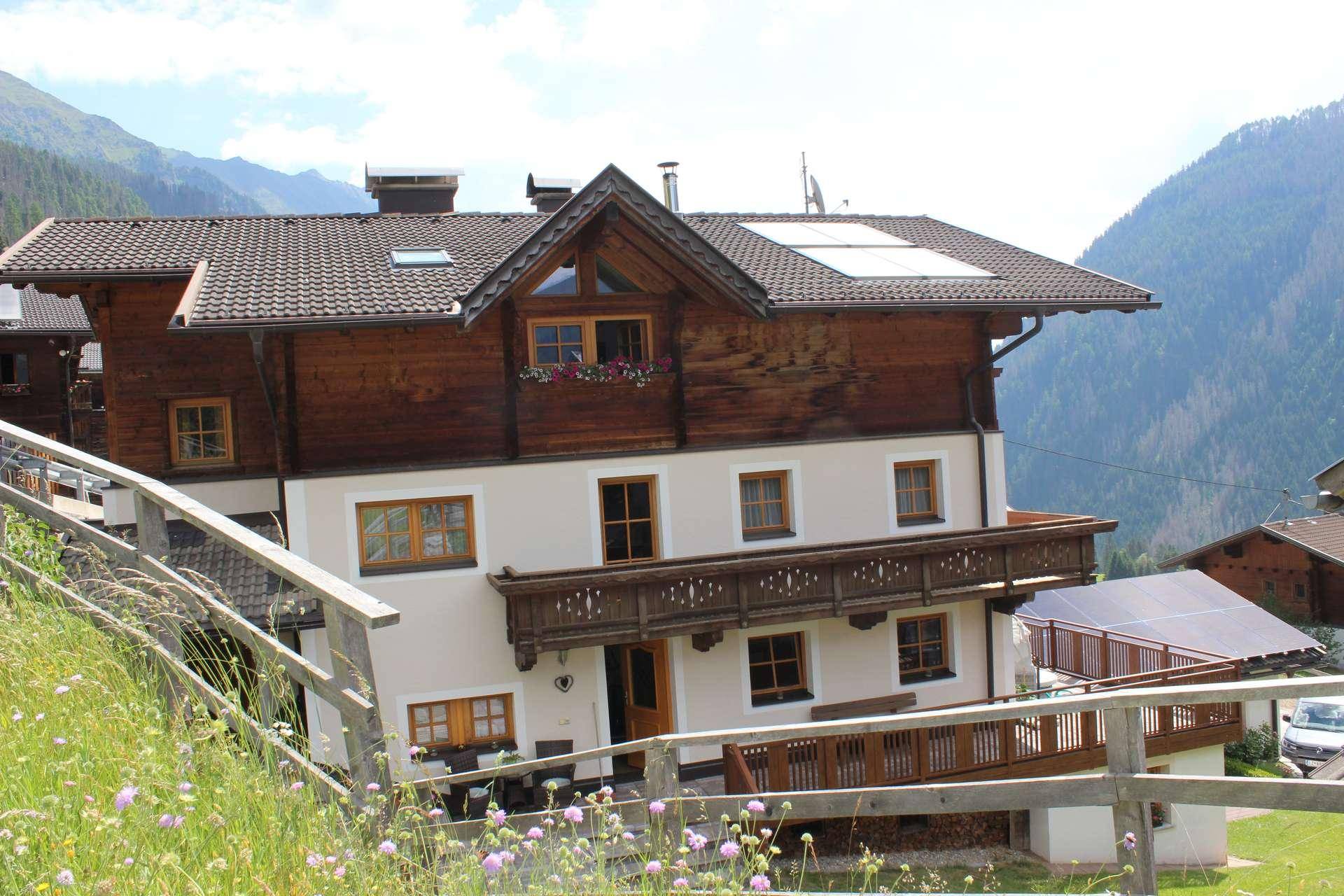 Traditionelles Haus mit Holzelementen, Balkonen und Solarpaneelen auf dem Dach in den Bergen.