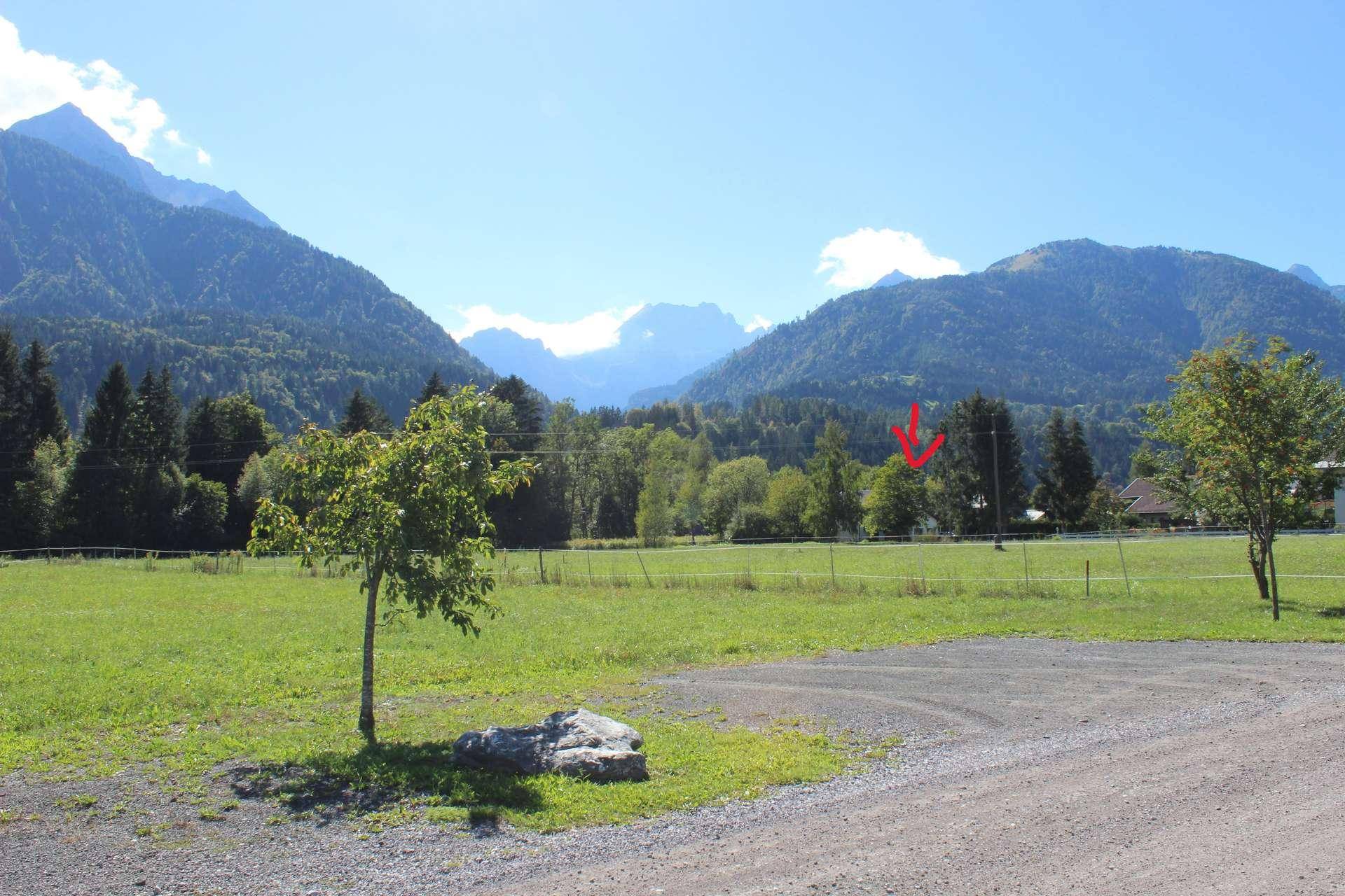 Panoramablick auf grüne Wiesen und Berge, mit einem Hinweis auf die Lage des Anwesens.