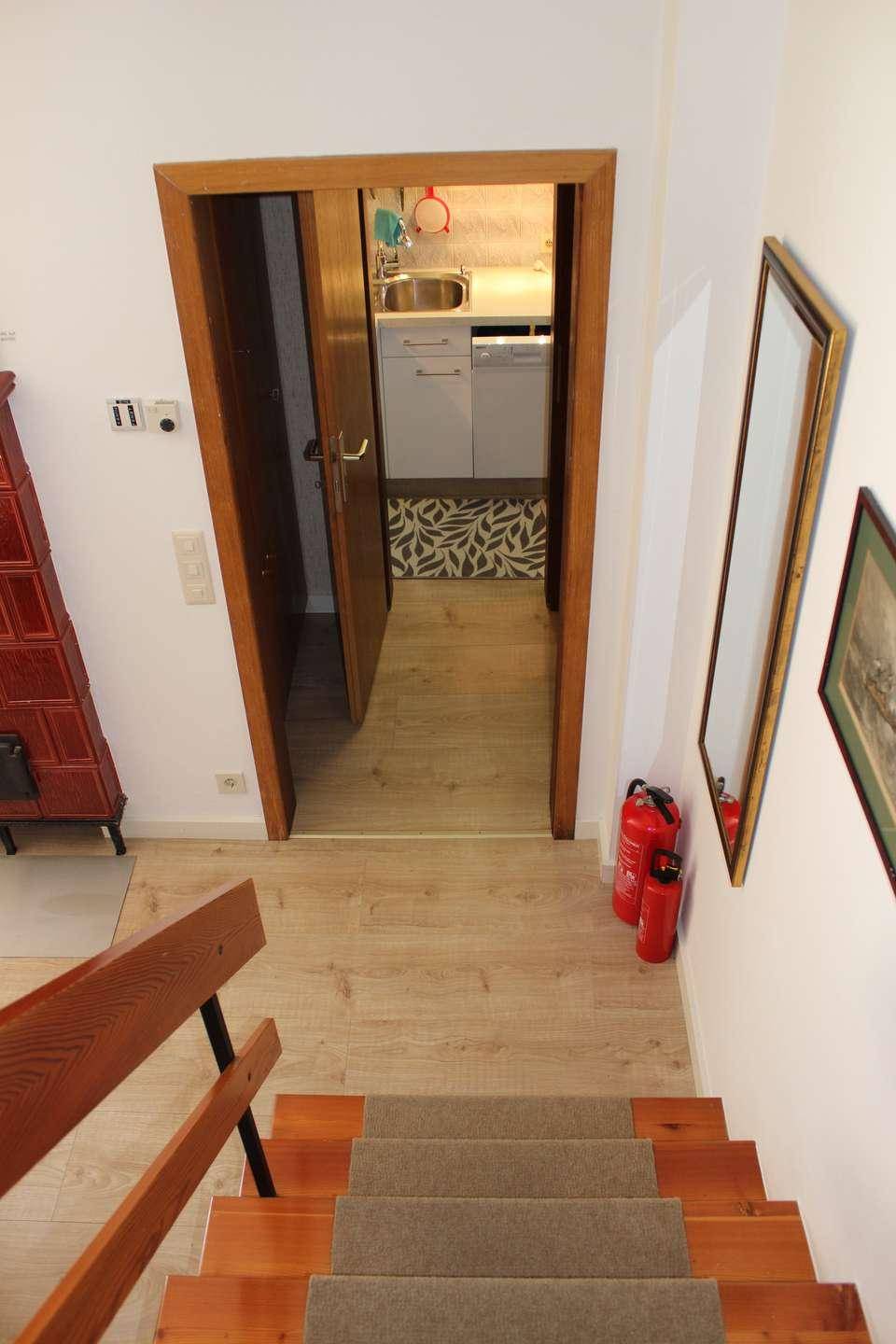 Treppenaufgang mit Holzstufen und Blick in einen kleinen Hauswirtschaftsraum.