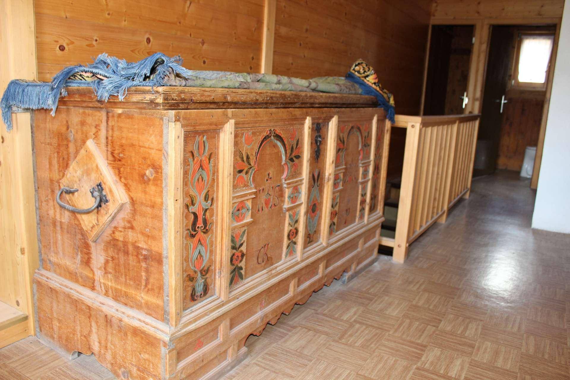 Innenflur oder Treppenabsatz mit einer großen, kunstvoll bemalten Holztruhe und Holzfußboden.