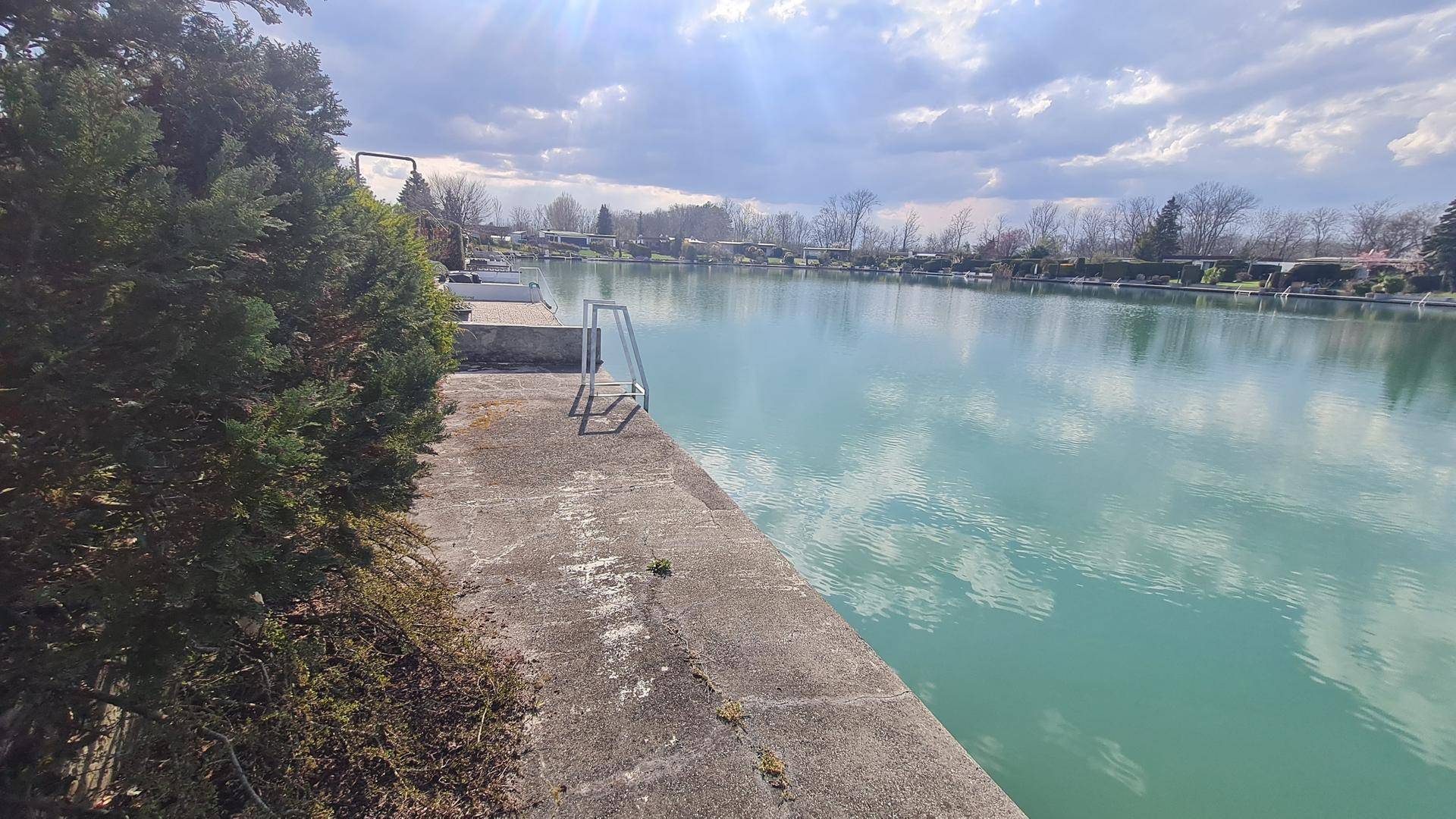 Weitläufiger Blick auf den See mit Steg und umliegender Natur.