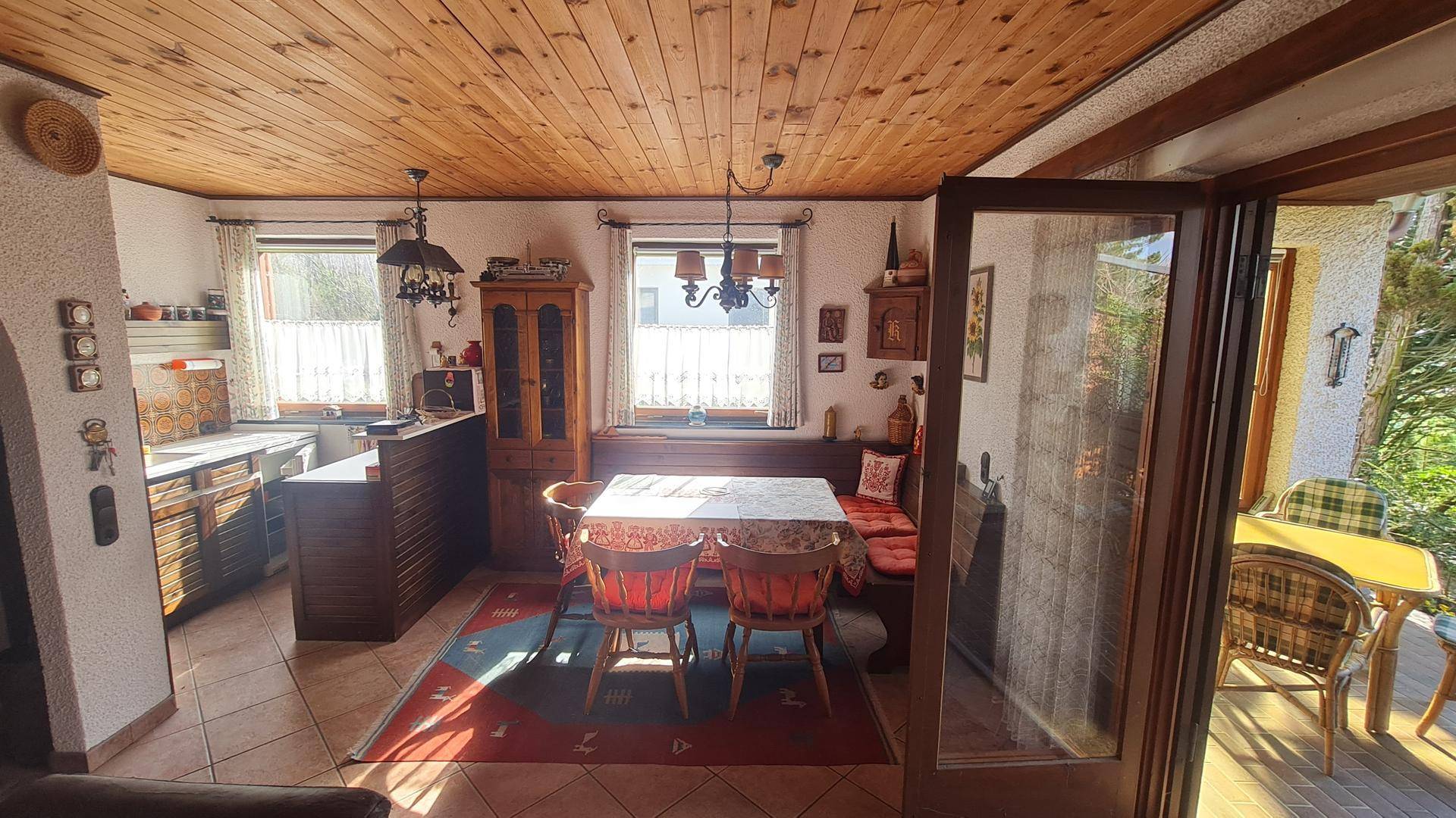 Offener Wohn- und Essbereich mit Holzbalkendecke, Esstisch und Zugang zur Terrasse.