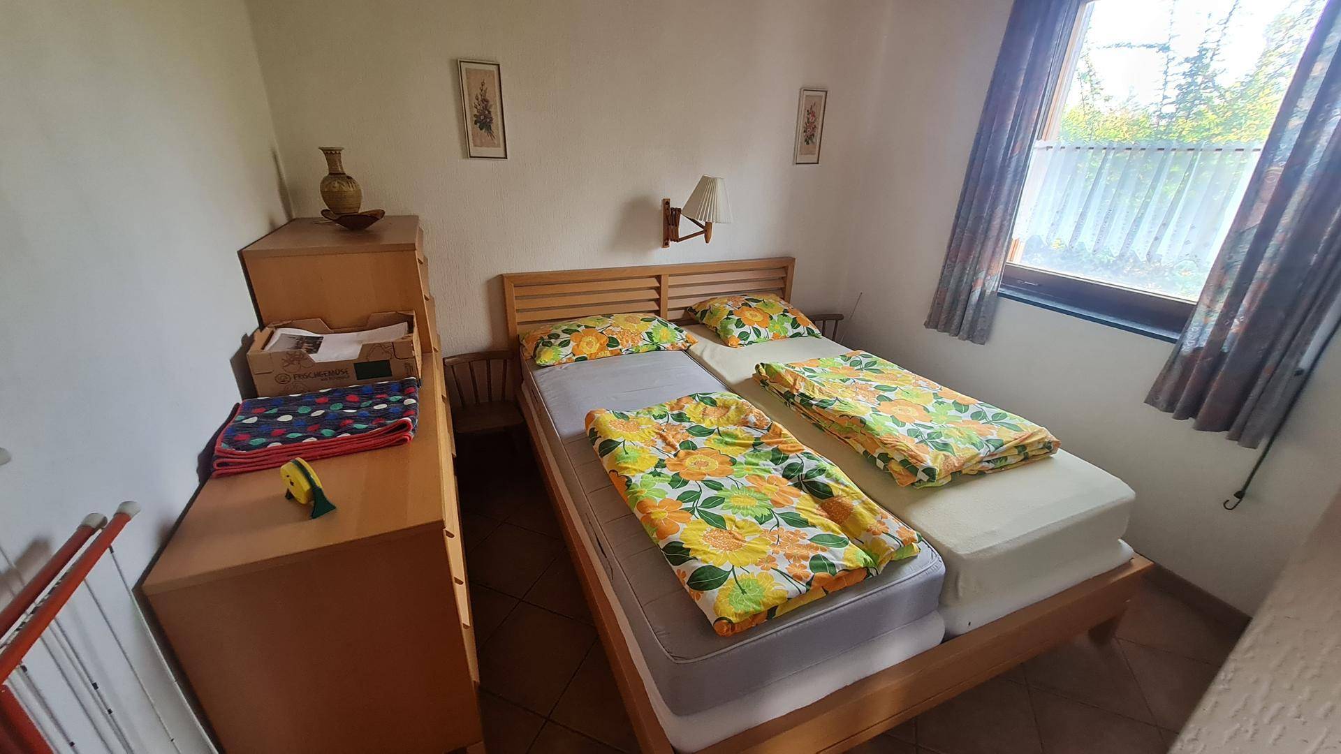 Schlafzimmer mit zwei Einzelbetten, Holzmöbeln und Fenster mit Blick ins Grüne.