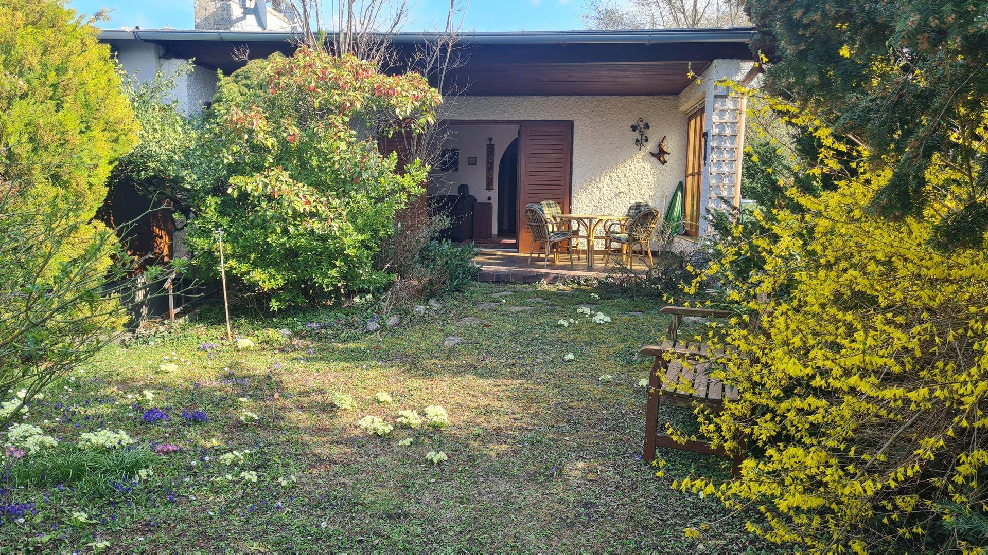 Gemütlicher Gartenbereich mit Sitzbank und Blick auf die überdachte Terrasse des Hauses.