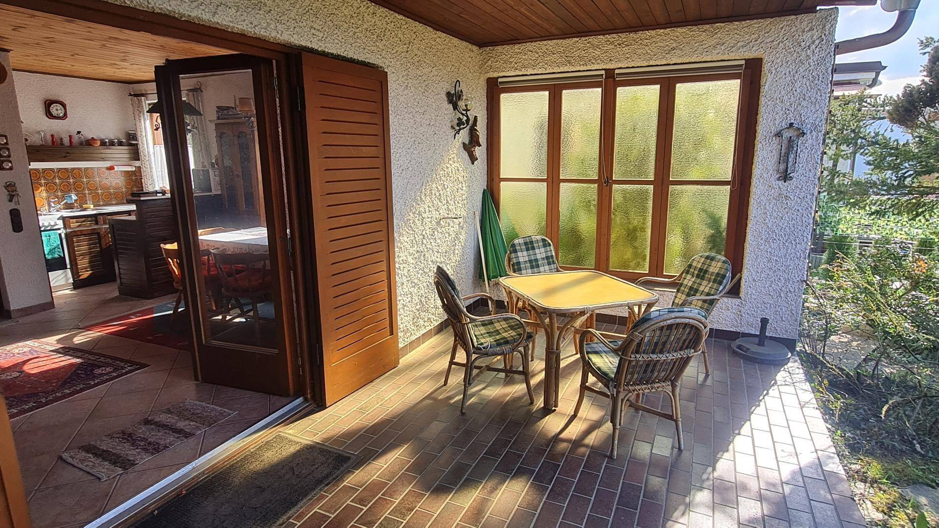 Helle, überdachte Terrasse mit Esstisch und Stühlen, ideal für Mahlzeiten im Freien.