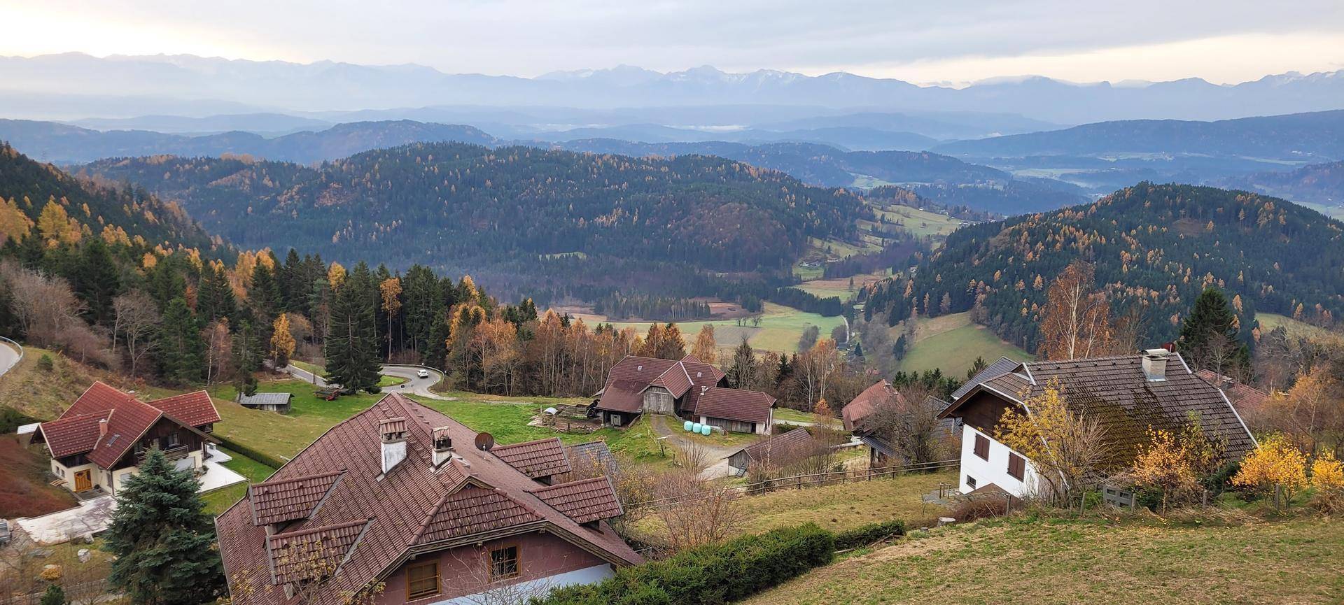 Panoramablick auf eine ländliche Siedlung inmitten bewaldeter Hügel und Berge.